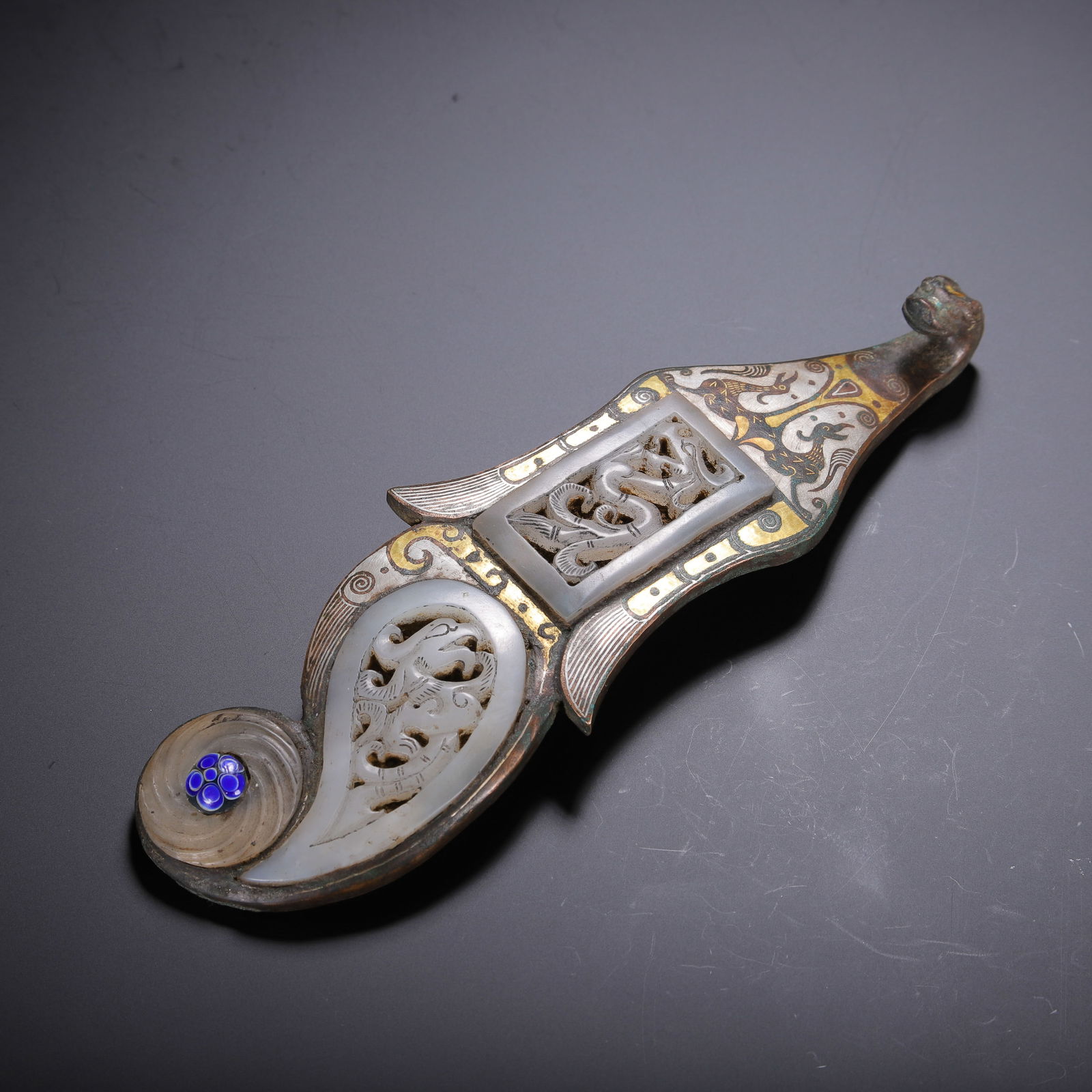 CHINESE BRONZE BELT HOOK WITH JADE & INLAY: Dimensions: L. 18 cm. Weight 350 grams. This elaborate Chinese bronze belt hook measures 18 cm in length and weighs 350 grams, featuring a masterful combination of gold-silver inlay and white jade inl