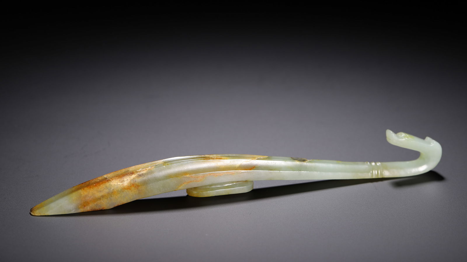 CHINESE HETIAN JADE BELT HOOK: Dimensions: L. 21 cm. W. 2 cm. Weight 70 grams. This elegant Chinese Hetian jade belt hook measures 21 cm in length, 2 cm in width, and weighs 70 grams, carved from pale celadon jade with