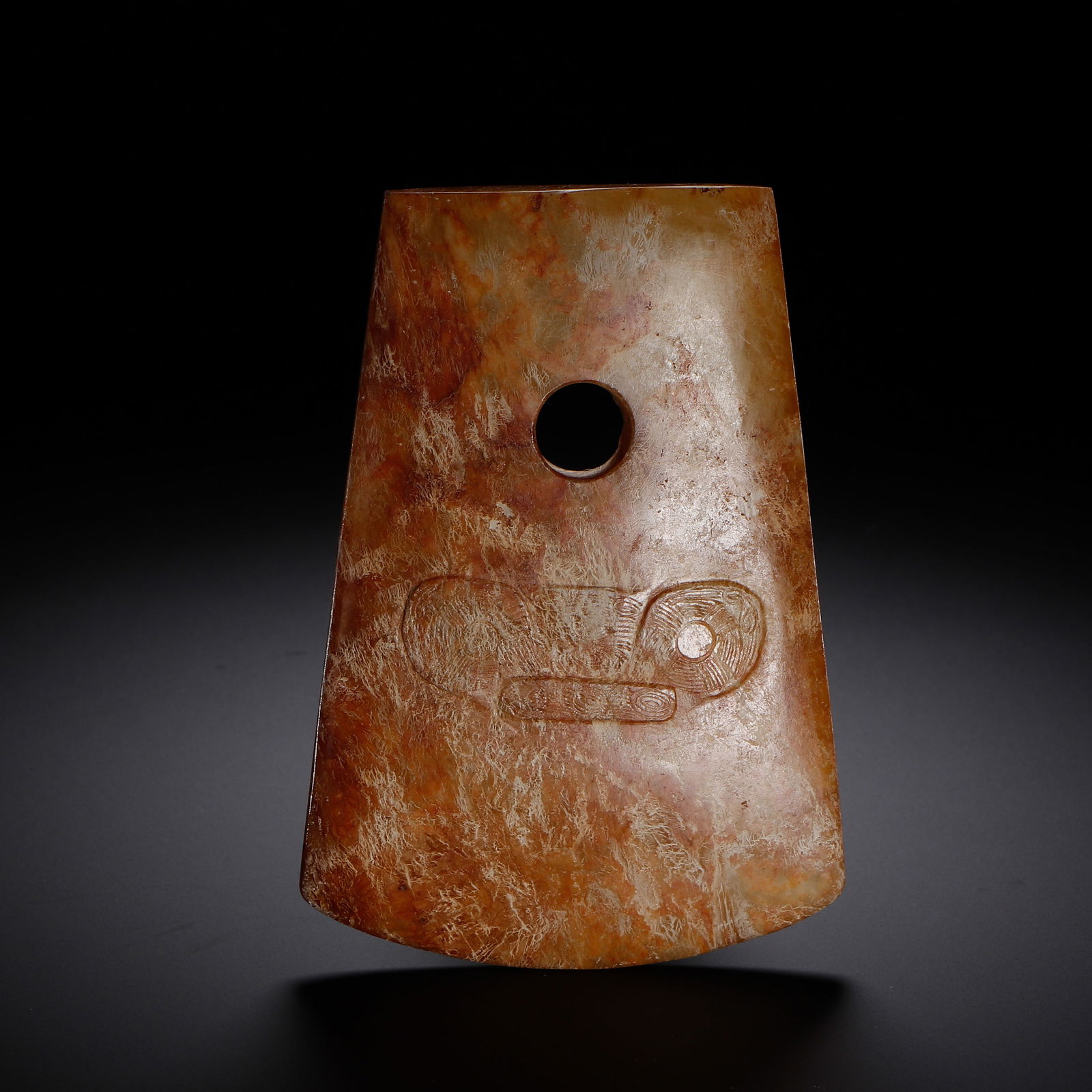 CHINESE JADE AXE CEREMONIAL BLADE: Dimensions: L. 12.2 cm. W. 8.5 cm. Weight 250 grams. This imposing Chinese jade axe ceremonial blade features a tapered rectangular form with a curved lower edge and a central perforation for