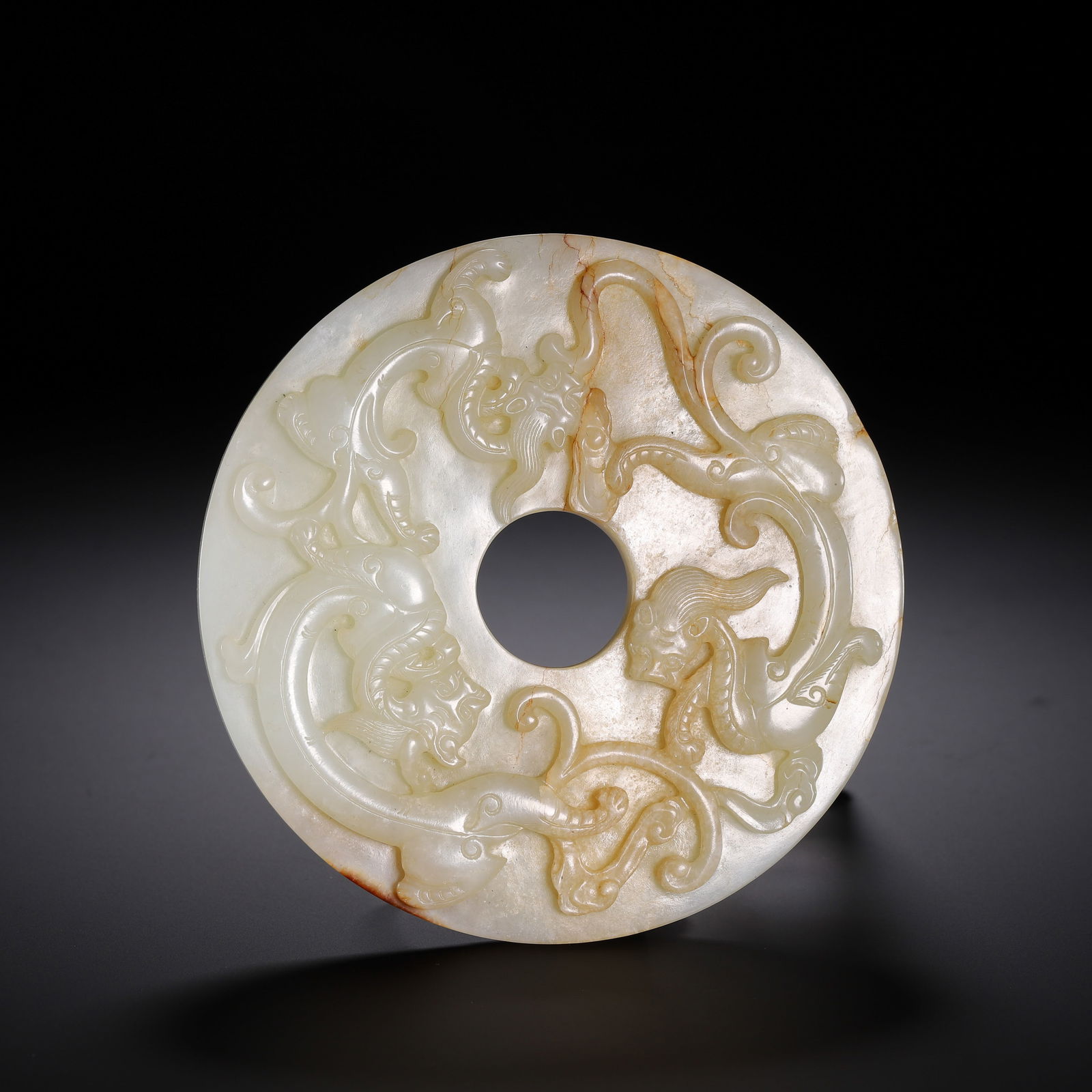 CHINESE JADE BI DISC WITH CHILONG: Dimensions: L. 12 cm. Weight 340 grams. This exquisite Chinese jade bi disc features high-relief carvings of sinuous chilong (interlaced dragons) that wind across the pale celadon jade surface,