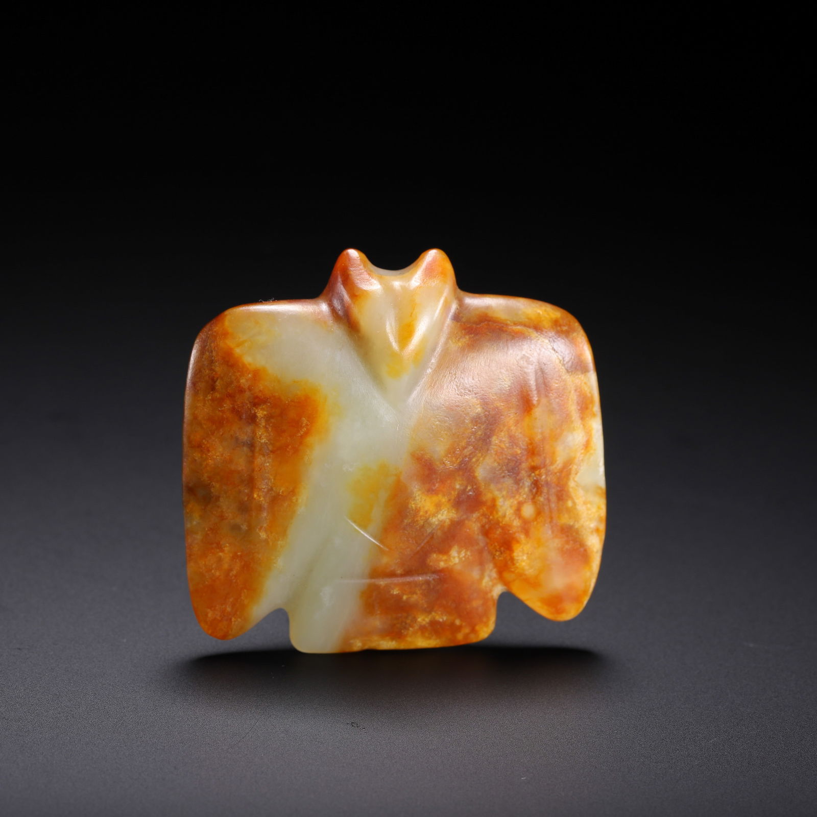 CHINESE JADE BIRD AMULET: Dimensions: L. 4.5 cm. W. 4.3 cm. Weight 30 grams. This striking Chinese jade bird amulet is carved in a stylized avian form, likely a mythical eagle or owl, with broad wings and a simplified
