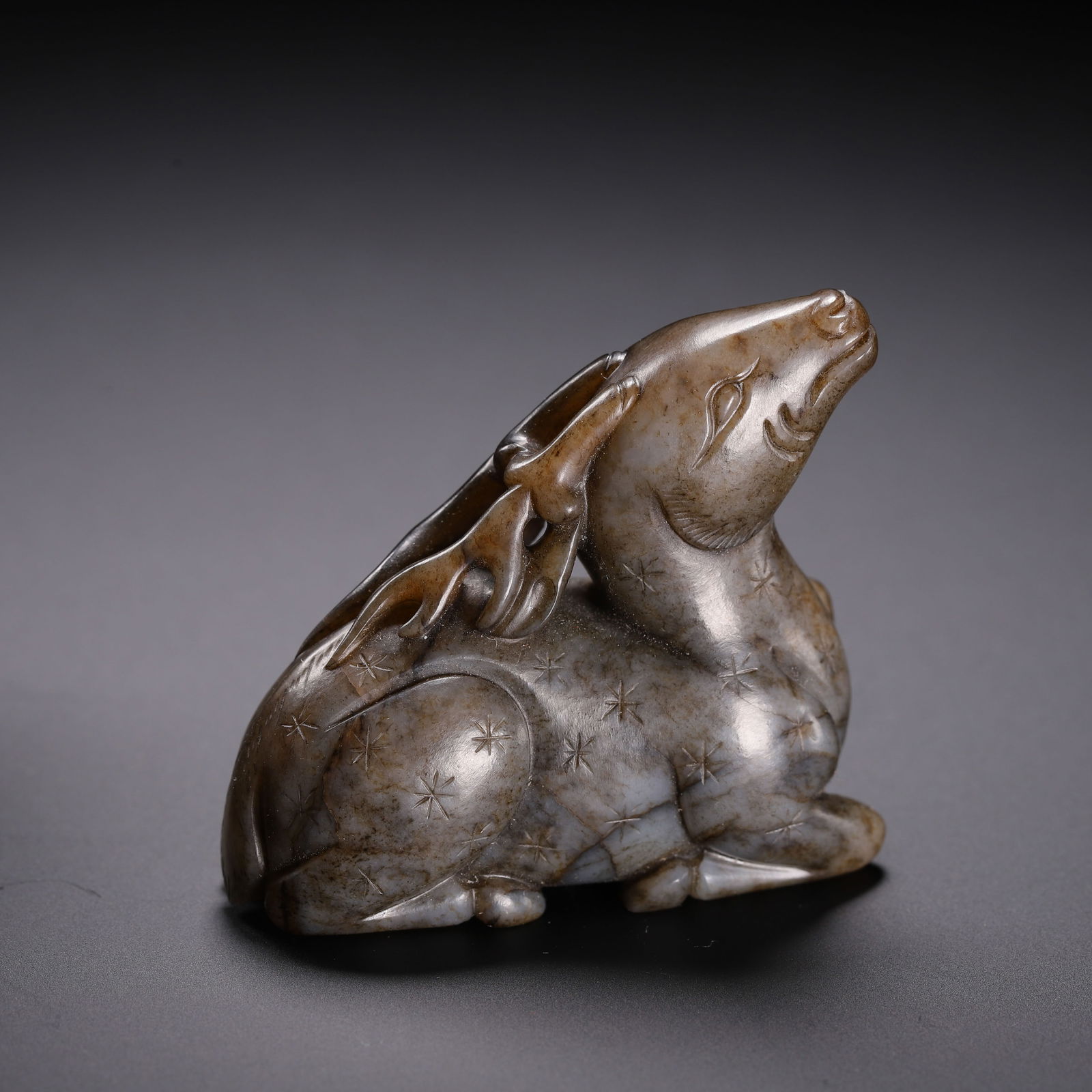 CHINESE JADE DEER CARVING: Dimensions: L. 2.2 cm. W. 2.2 cm. H. 4.2 cm. Weight 60 grams. This delicate Chinese jade deer carving is sculpted in a recumbent pose with its head raised skyward, detailed with incised star