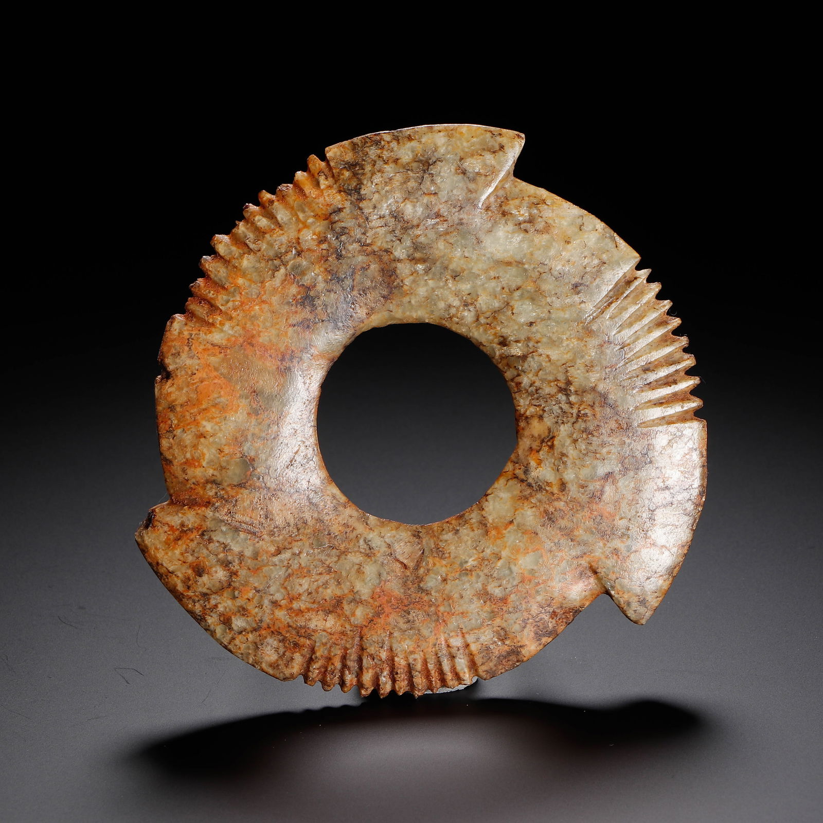 CHINESE JADE NOTCHED BI DISC: Dimensions: L. 10 cm. Weight 70 grams. This distinctive Chinese jade notched bi disc features a classic circular form with a central aperture, enhanced by carved serrated edges and projecting