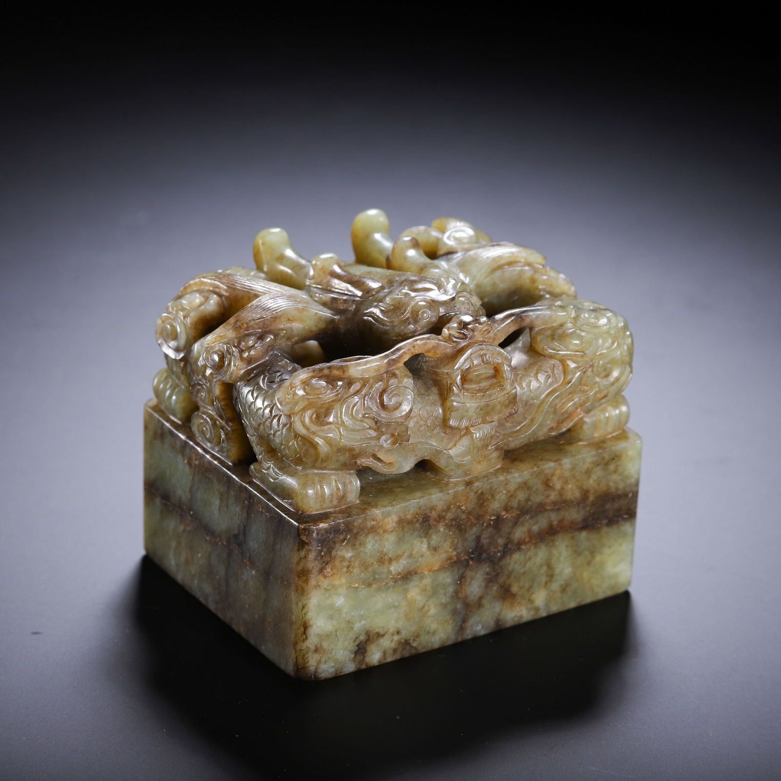 CHINESE HETIAN JADE DRAGON SEAL: Dimensions: L. 7.5 cm. W. 6 cm. H. 6 cm. Weight 580 grams. This imposing Chinese Hetian jade seal features a square base surmounted by a reticulated carving of interlocking dragons with detailed scale