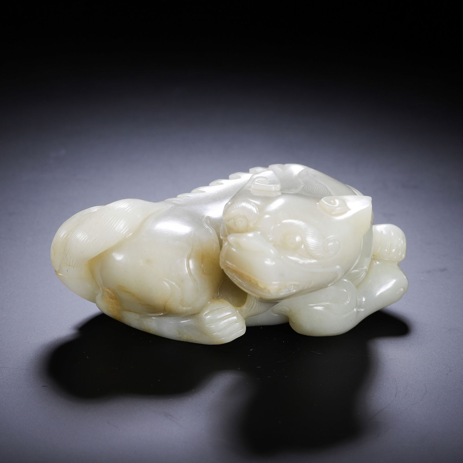 CHINESE HETIAN JADE MYTHICAL BEAST: Dimensions: L. 11 cm. W. 8 cm. H. 5 cm. Weight 500 grams. This powerful Chinese Hetian white jade carving depicts a recumbent pixiu (mythical guardian beast), with detailed incised fur, a muscular bod