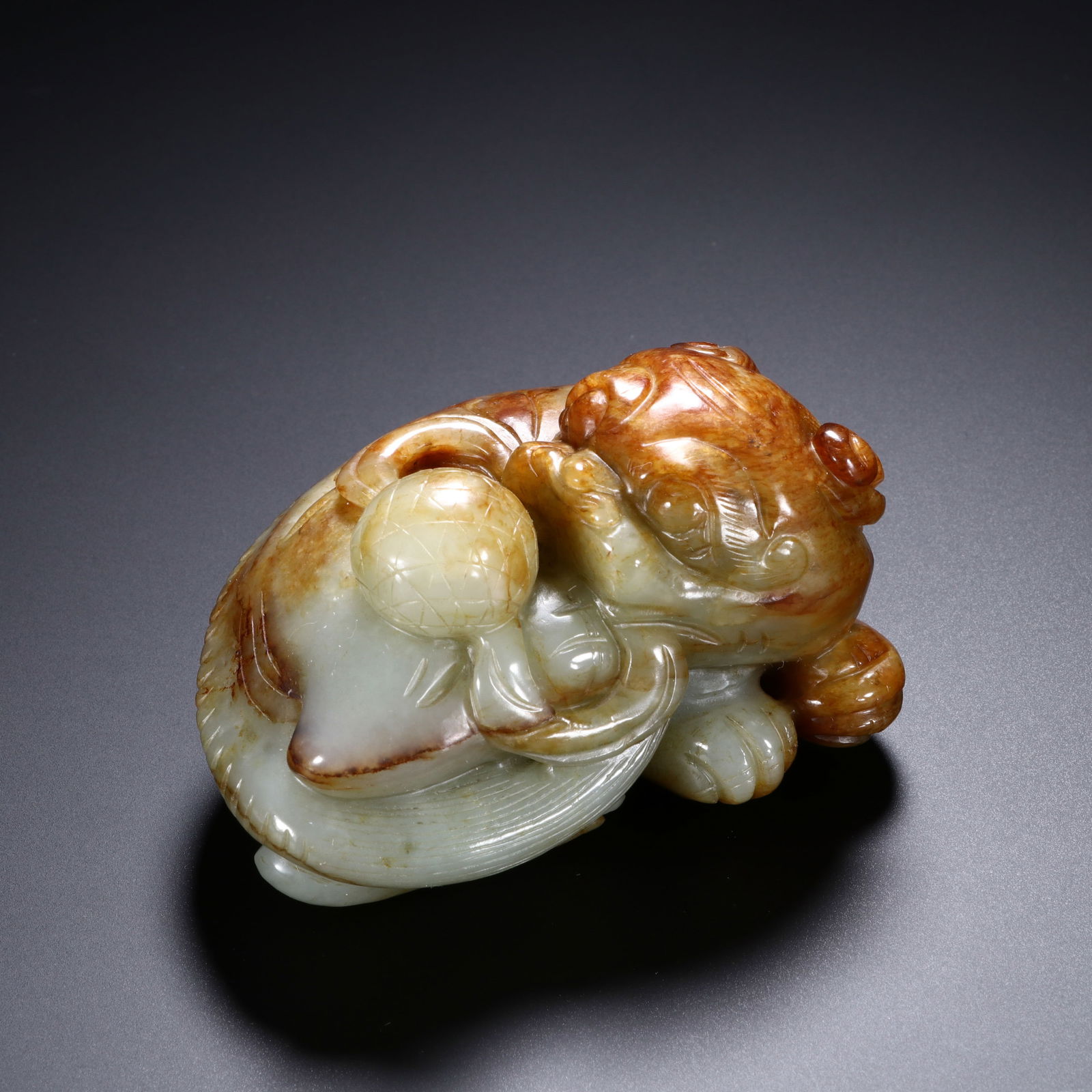 CHINESE HETIAN JADE MYTHICAL BEAST: Dimensions: H. 5 cm. W. 8.5 cm. This captivating Chinese Hetian jade mythical beast measures 5 cm in height and 8.5 cm in width, carved from Hetian jade with striking russet skin that contrasts beauti