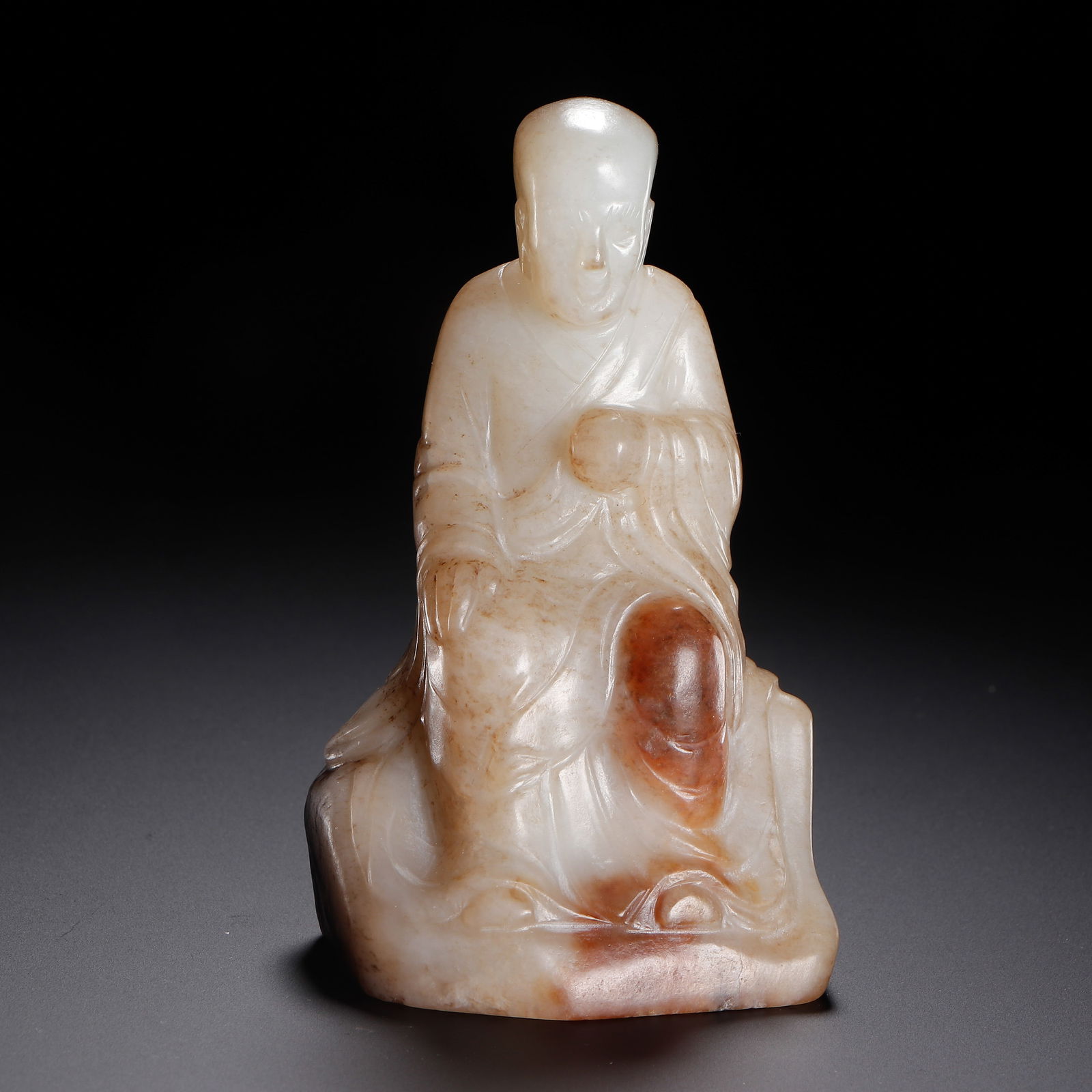 CHINESE HETIAN JADE LUOHAN FIGURE: Dimensions: L. 5.5 cm. W. 4 cm. H. 9.5 cm. Weight 210 grams. This serene Chinese Hetian jade carving depicts a seated luohan (arhat) with a calm facial expression and flowing robe drapery, masterfully
