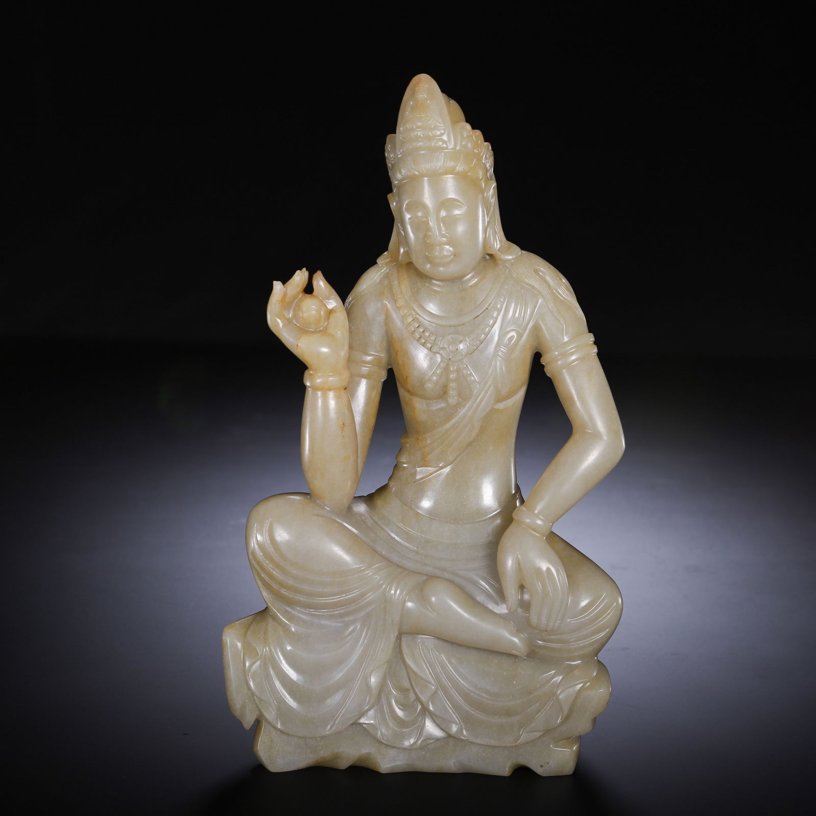 CHINESE HETIAN JADE GUANYIN STATUE: Dimensions: L. 11 cm. W. 5 cm. H. 19 cm. Weight 1010 grams. This serene Chinese Hetian jade carving depicts Guanyin in a relaxed lotus pose (lalitasana), with delicate detailing of the headdress, bead