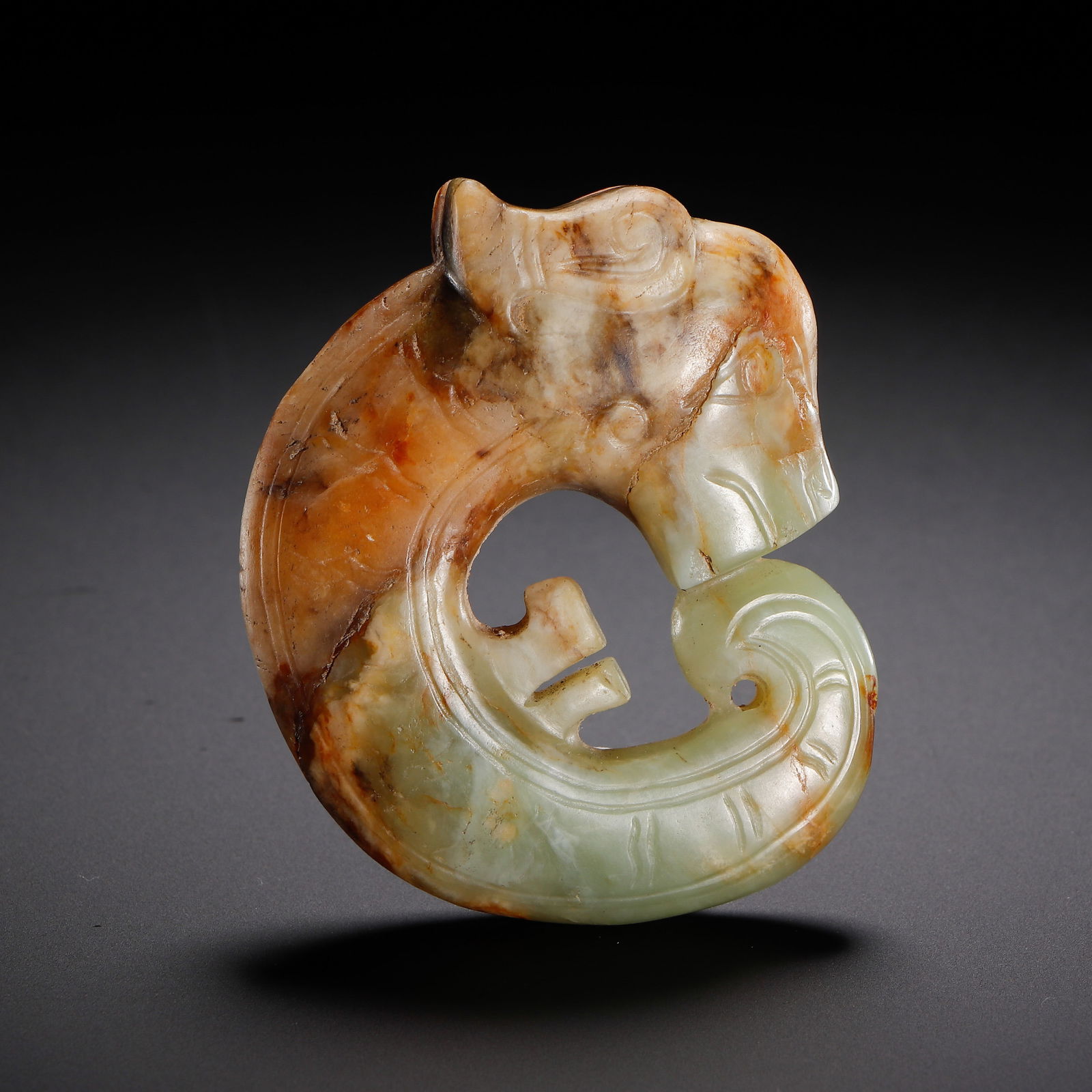 CHINESE HETIAN JADE PIG DRAGON: Dimensions: L. 6.8 cm. This archetypal Chinese Hetian jade carving depicts a "pig dragon" (zhu long), a iconic symbol of the Hongshan culture, with a C-shaped body, stylized pig-like head, and incised