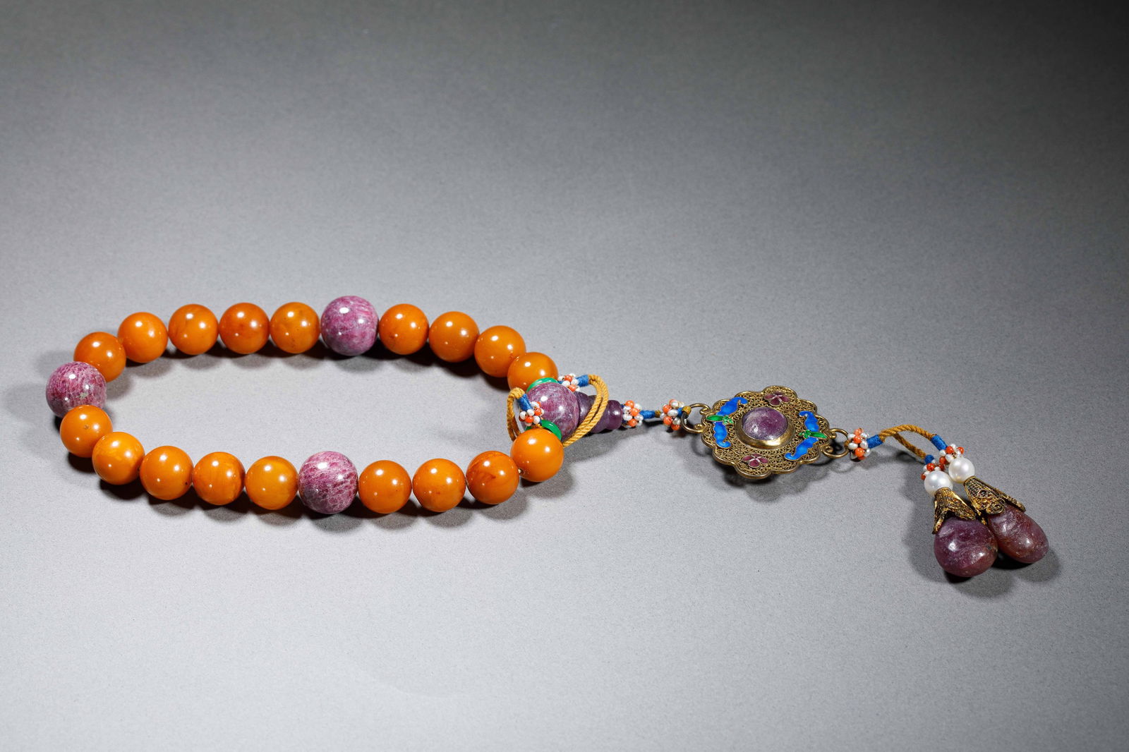 CHINESE AMBER BEADED PRAYER BRACELET: Dimensions: L. 1.2 cm. Weight 90 grams. This Chinese amber beaded prayer bracelet features spherical amber beads (1.2 cm each) accented with vibrant ruby zoisite spacer beads, weighing 90 grams total.
