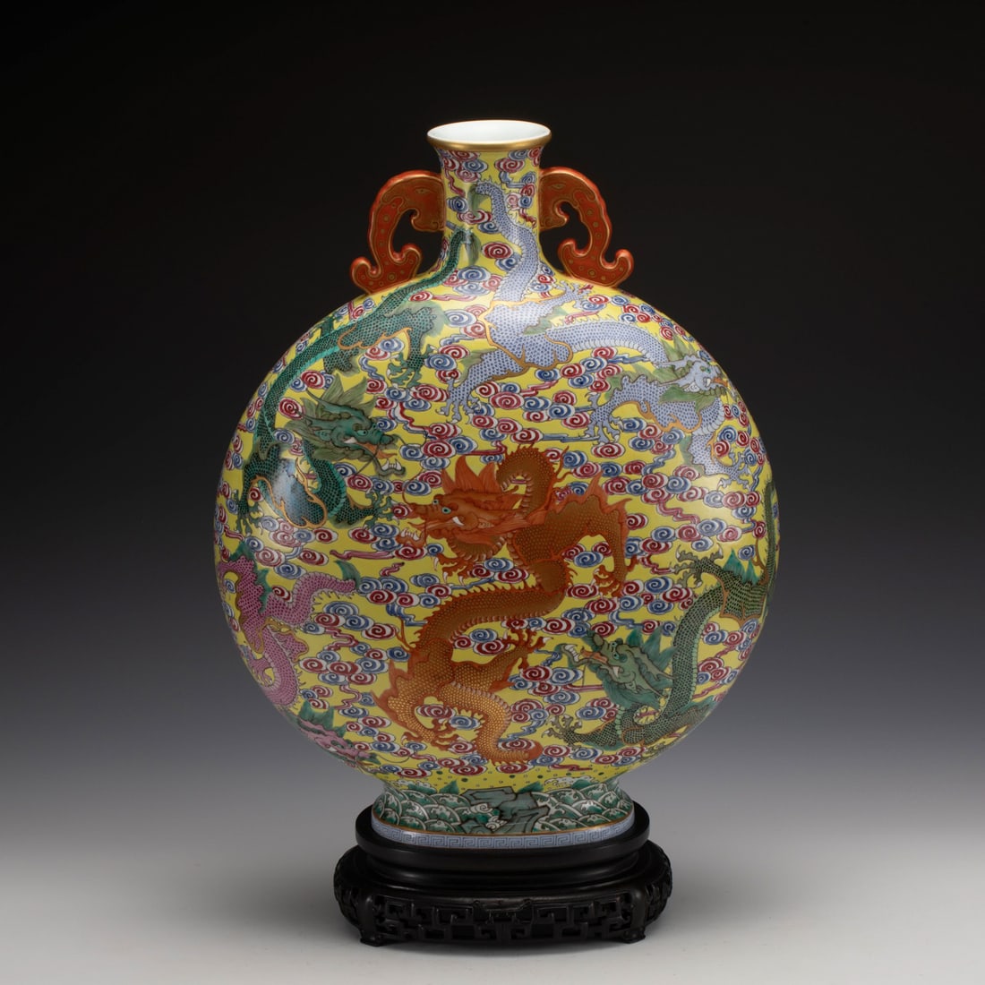 FAMILLE JAUNE DRAGON MOON VASE ON STAND: Measurements: Length: 38.2 cm, Width: 19.8 cm, Height: 49.2 cm Chinese Famille Jaune Porcelain Moon Vase On Carved Hardwood Stand. The porcelain potted in moon vase, flat globular moon lower belly,