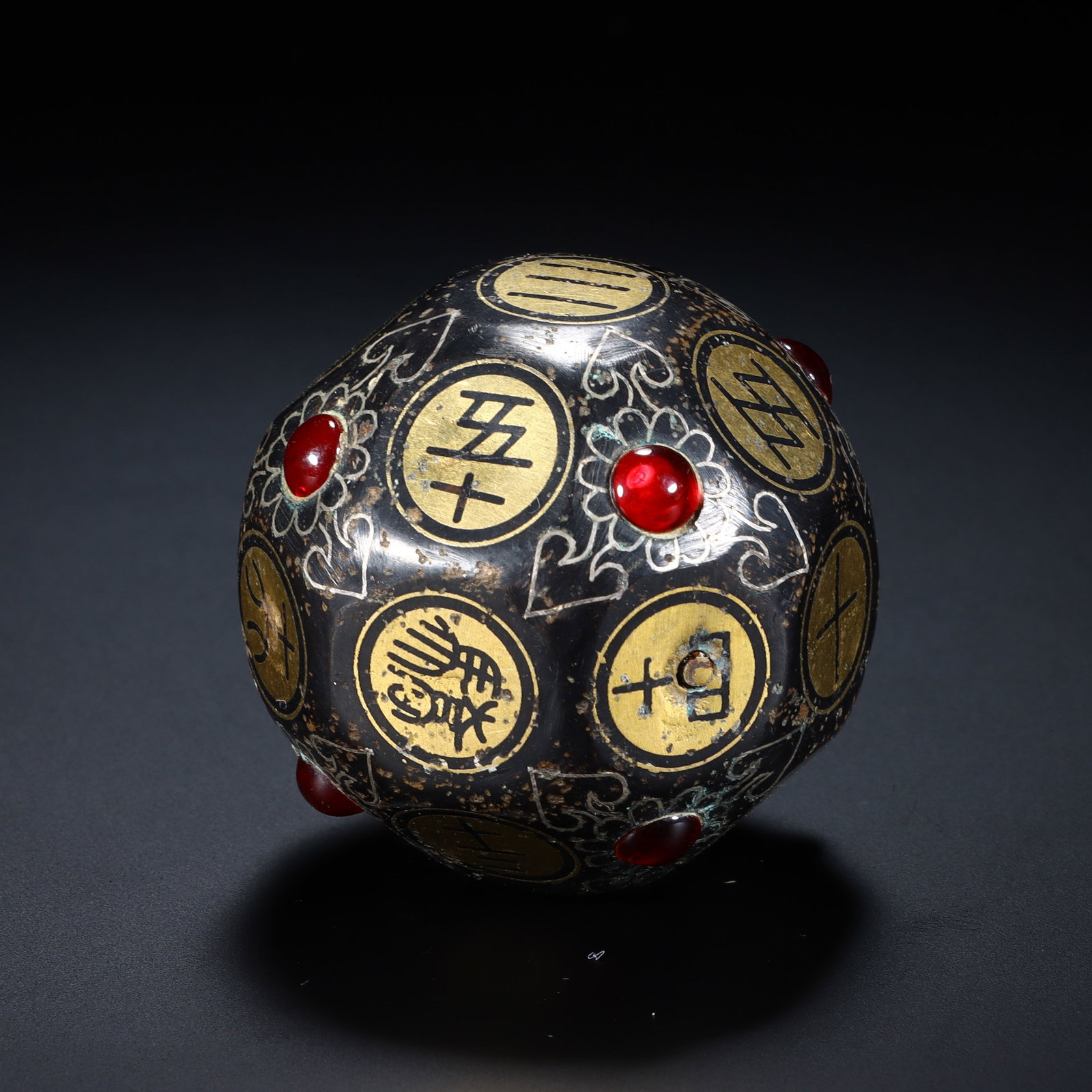 A CHINESE GOLD & SILVER-INLAID BRONZE DIE: Dimensions: Diam. 4.1 cm. This is an exceptional Chinese gold and silver-inlaid bronze die, measuring 4.1 cm in diameter. The polyhedral gaming piece is crafted from bronze with a rich, aged patina, i