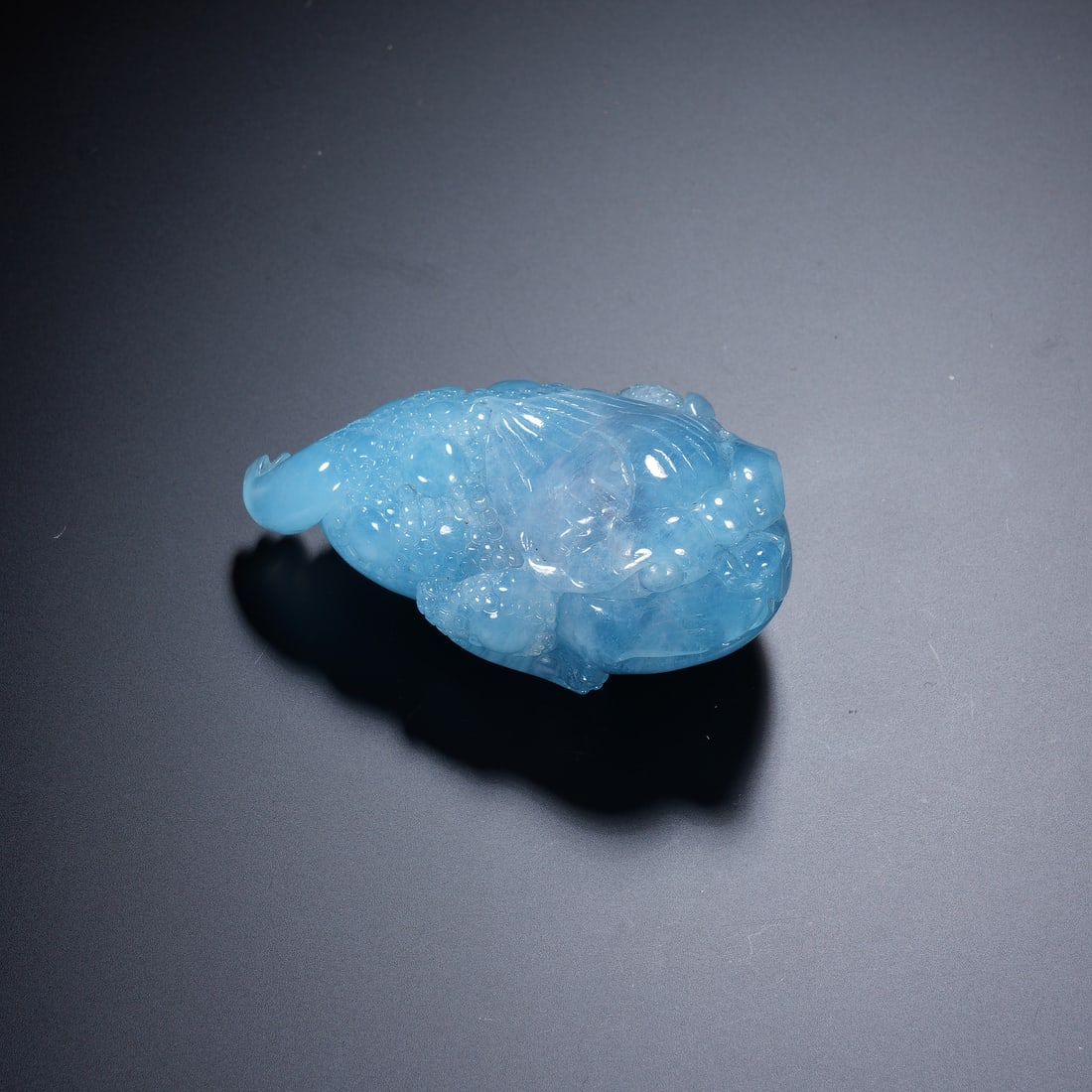 A CHINESE AQUAMARINE GOLDEN TOAD CARVING: Dimensions: 7x3x4.5 cm Weight 97 grams. This exquisite Chinese carving is expertly fashioned from a single piece of luminous aquamarine, depicting a mythical golden toad (jin chan), a symbol of prospe