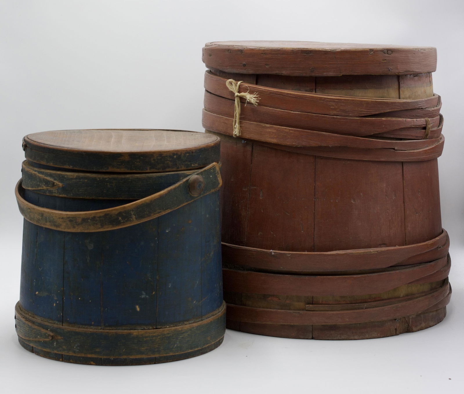 TWO PAINTED WOOD FIRKINS WITH COVERS.: American, 19th Century. The smaller with staved construction, single-lapped bands, and beautiful, original blue paint with bentwood handle. The larger with staved construction, unusual overlapping fin