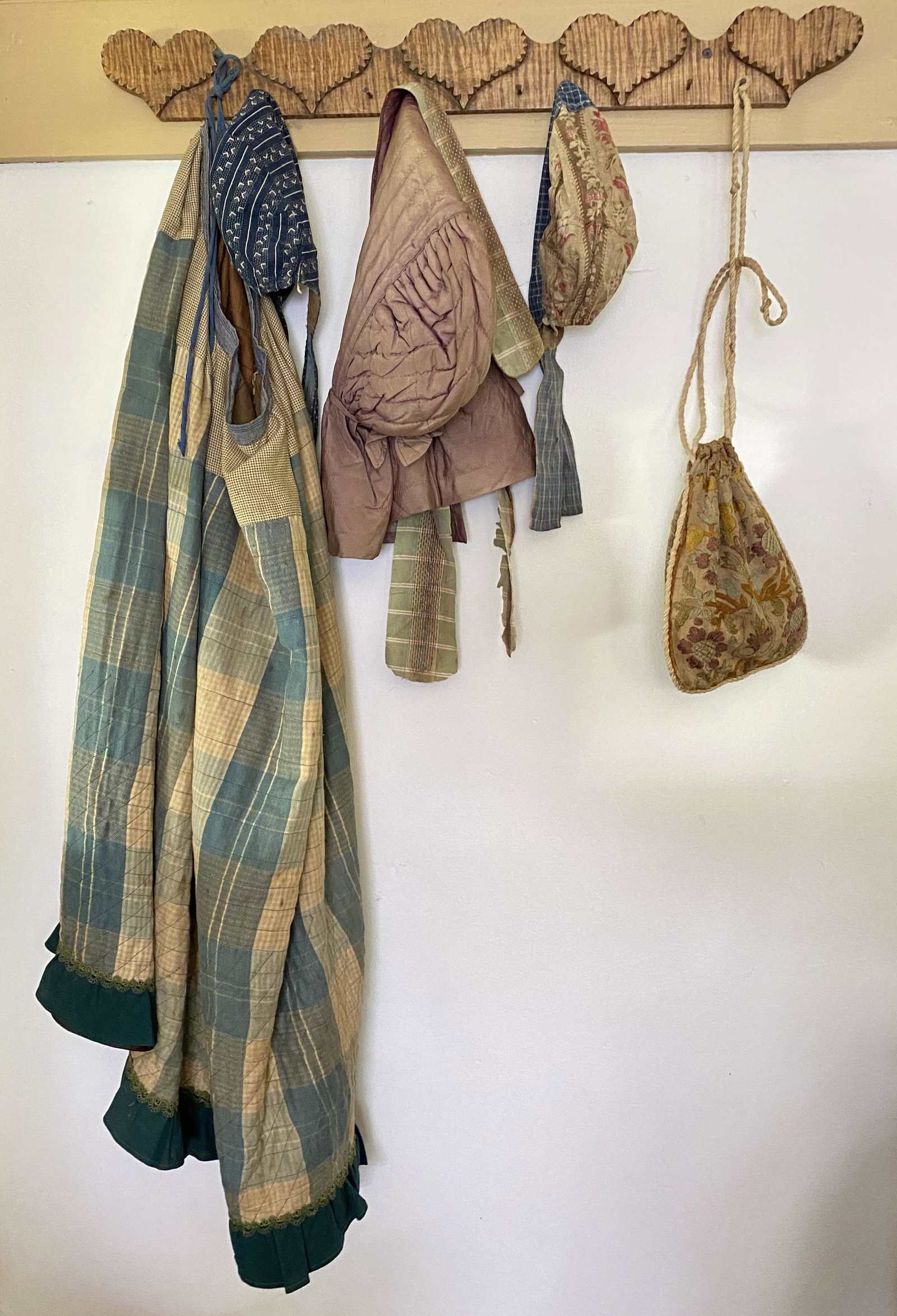 SET OF BONNETS, CREWEL PURSE, AND HOMESPUN SKIRT.: American (Pennsylvania), 19th Century. Three bonnets, crewel purse, and machine-stitched skirt. Largest 34.5"h. Smallest 16.5"h.