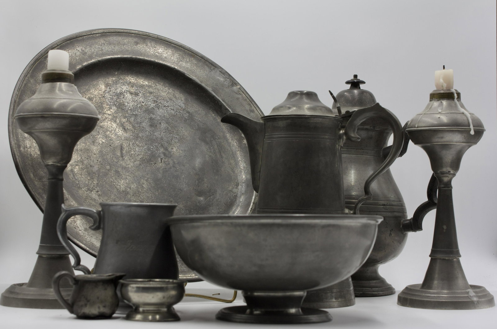 GROUP OF PEWTER ITEMS.: American. Group of eight: (1) pewter tea pot, A. Griswold stamped with eagle; (2 & 3) pair of pewter lamps; (4) mug; (5) pewter charger; (6) master salt; (7) miniature creamer; (8) benedict bowl. Smal