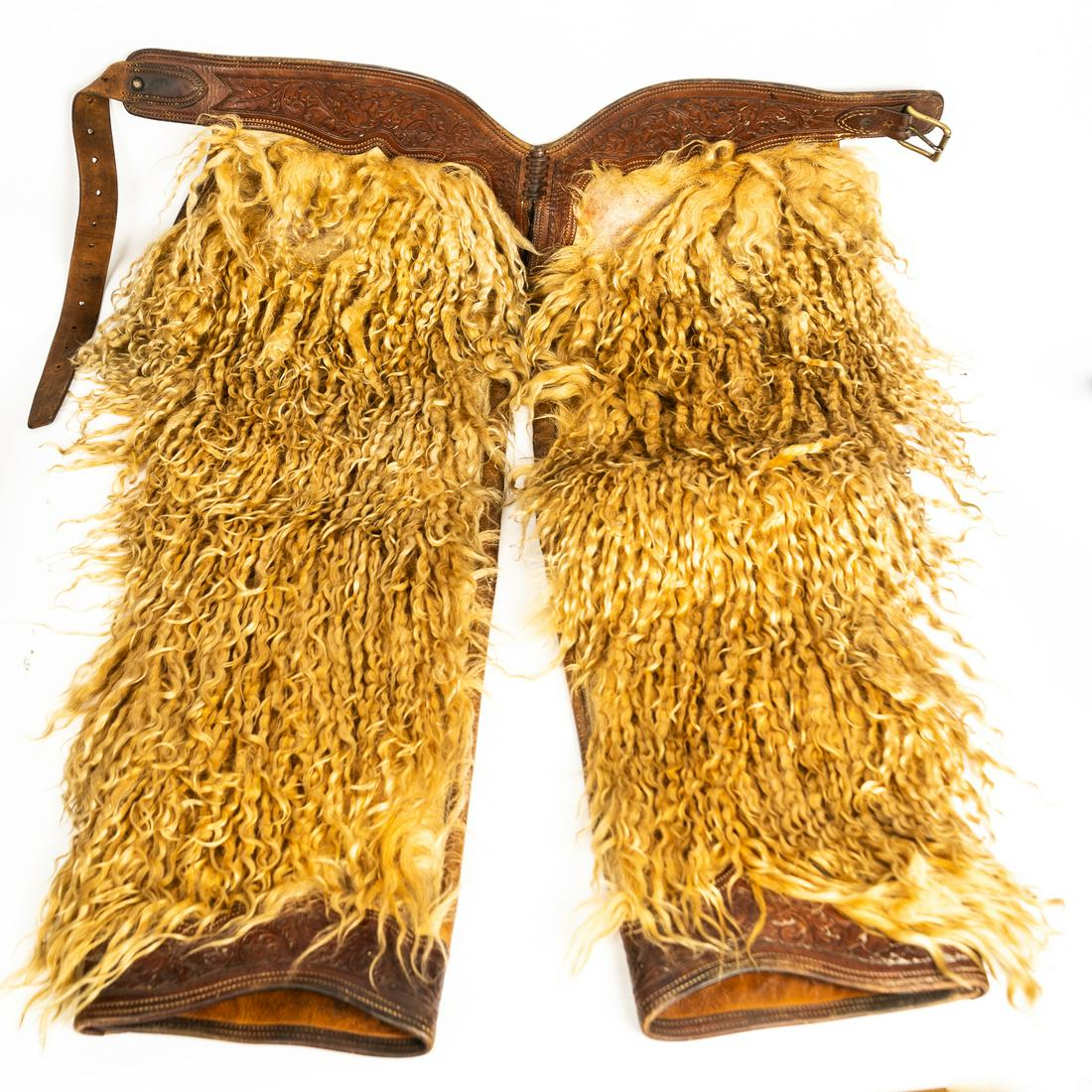 ANGORA WOOLY CHAPS.: American, early 20th century. Angora wooly chaps with tooled leather belt and cuffs. Good condition, with mild wear to upper portion. 31"w x 42" l, belt 50".