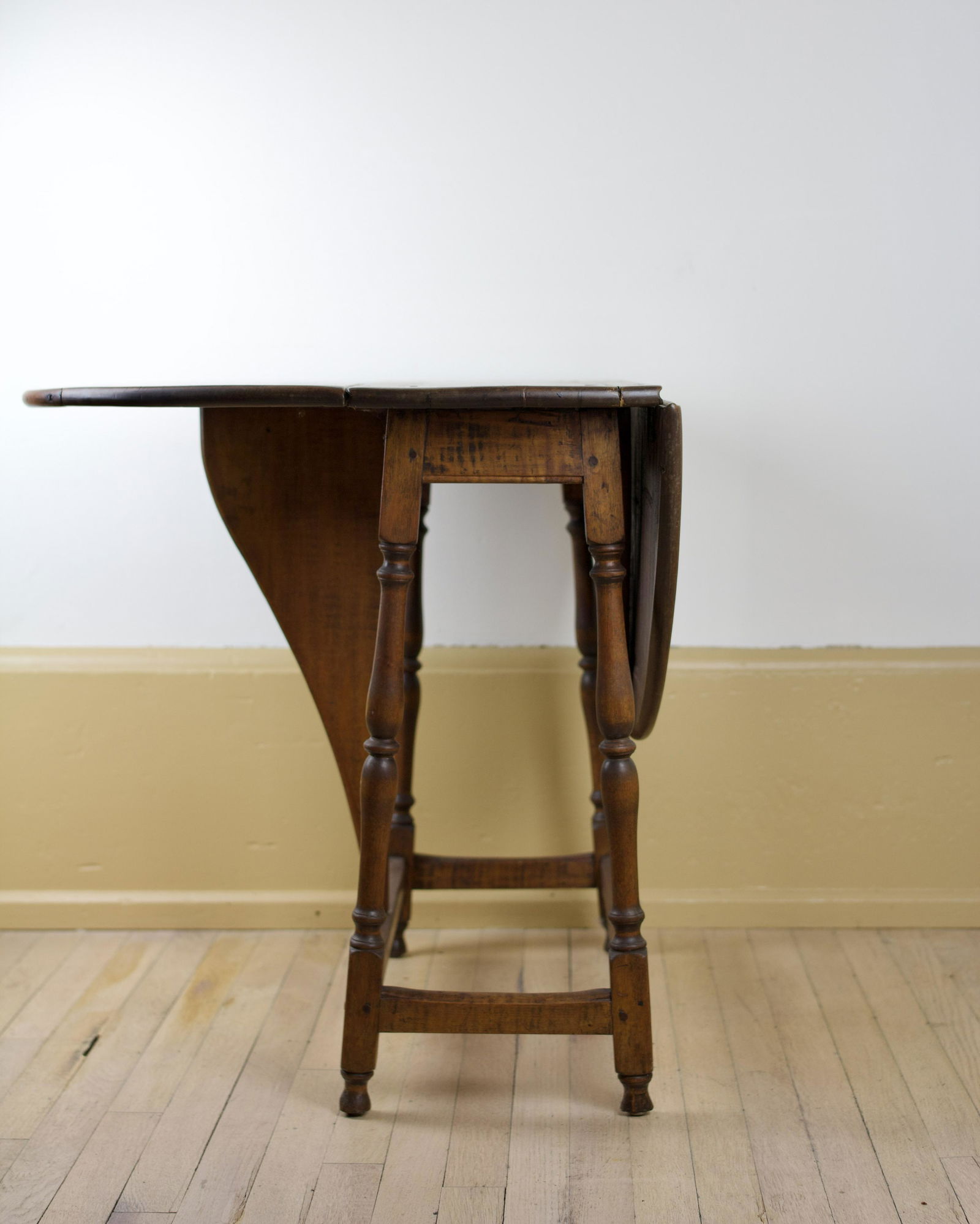 WILLIAM AND MARY MAPLE AND TIGER MAPLE BUTTERFLY TAVERN TABLE.: American (New England), 18th Century. The molded edged oblong top with hinged leaves above a plain skirt raised on splayed, turned legs joined by a box stretcher with a pair of tiger maple butterfly-s