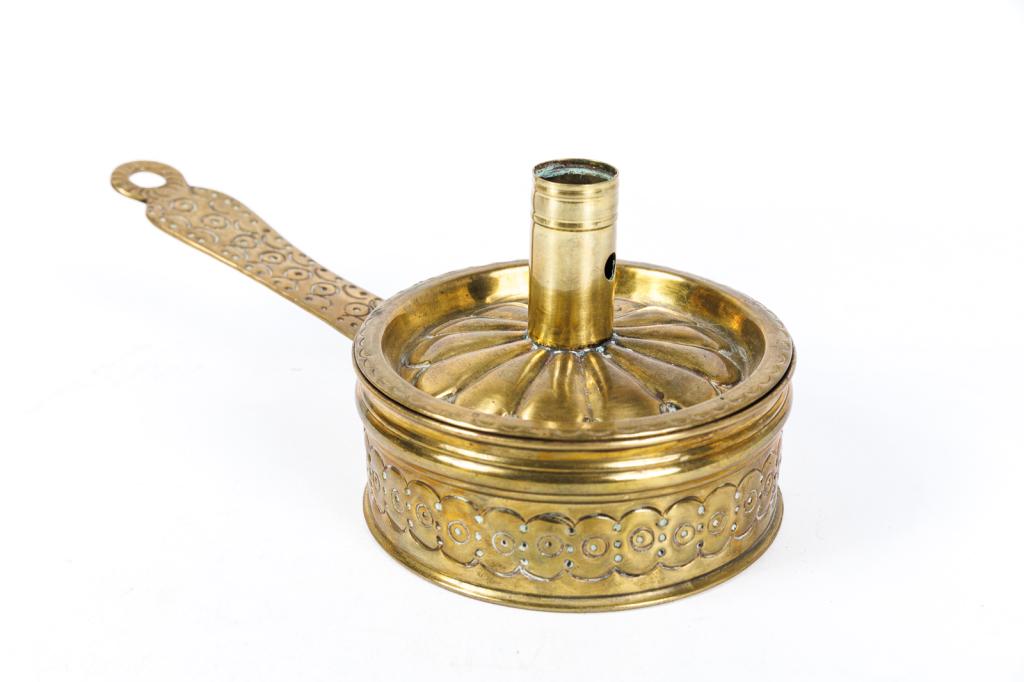BRASS TINDERBOX CANDLESTICK.: European, 18th Century. Candle socket lid with elaborate embossed decoration. Includes rams-horn striker and flint. 4.25”d. 9.5" with handle.