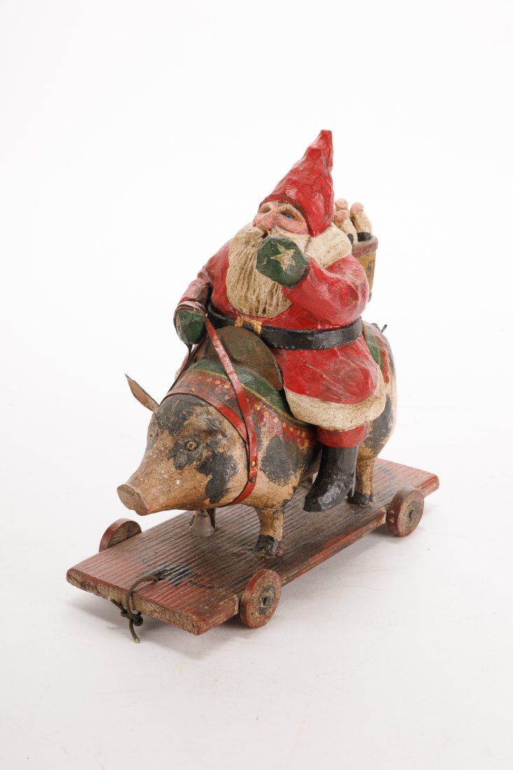 FOLK ART CHRISTMAS-THEMED CARVED AND PAINTED WHEELED TOY BY L.W. "LOU" SCHIFFERL (1931-__).: FOLK ART CHRISTMAS-THEMED CARVED AND PAINTED WHEELED TOY BY L.W. "LOU" SCHIFFERL (1931-__). American (Wisconsin), 20th - 21st Century. Wood, paint, textile, metal. Full-bodied German Santa Claus (Fath