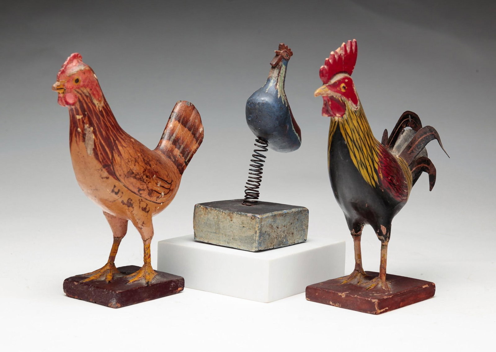 THREE CARVED AND PAINTED CHICKENS.: American, early 20th Century (circa 1900). A rooster with tin tail feathers in original red, yellow, and black paint, some wear and comb chips. 7.25"h. A hen in original worn paint and beak chip. 6.5"