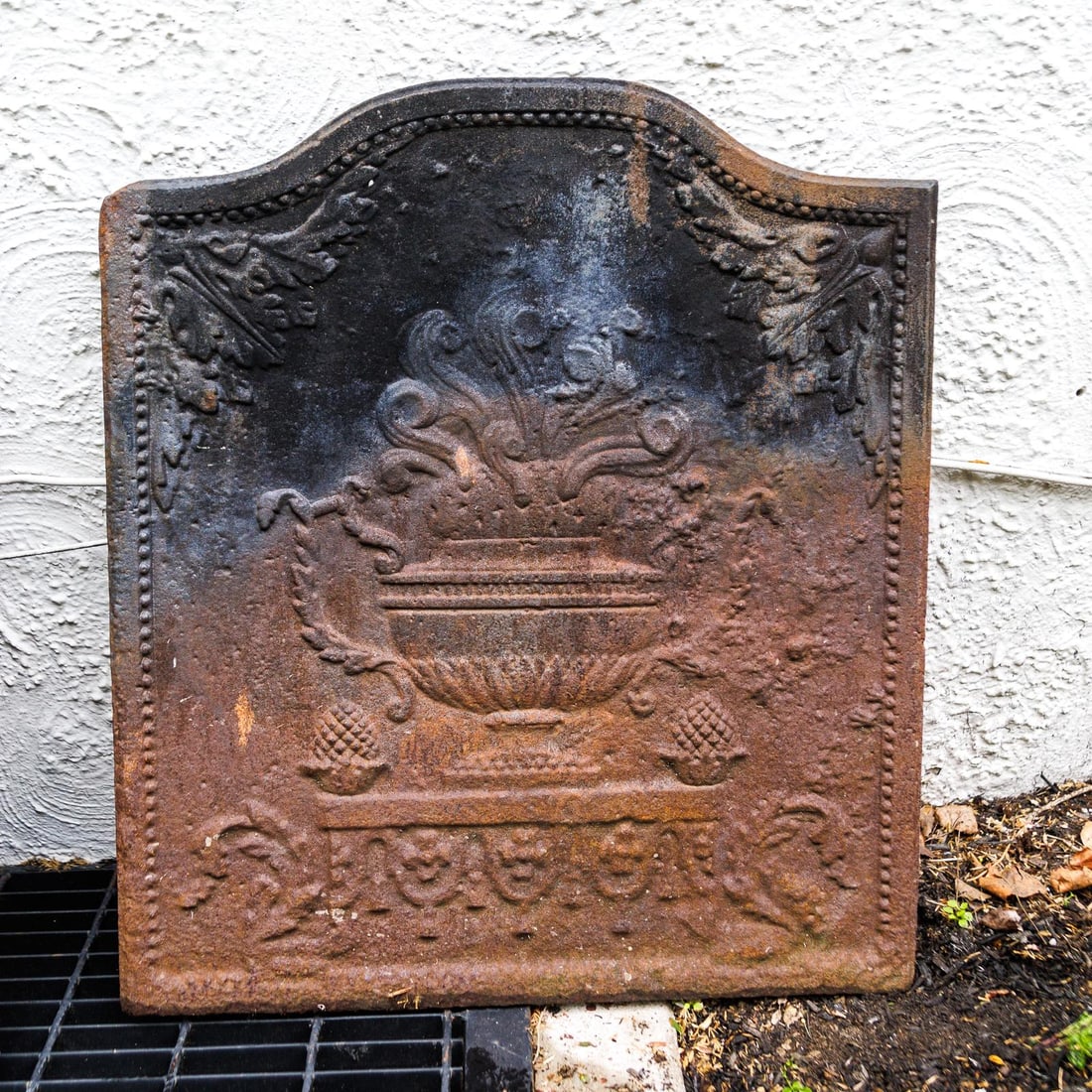 CAST IRON FIREBACK.: European,19th Century. With segmental arch, double-handled flower urn on pedestal with acorn finials and acorn leaves throughout, beaded border. 24.5"w. 28h."