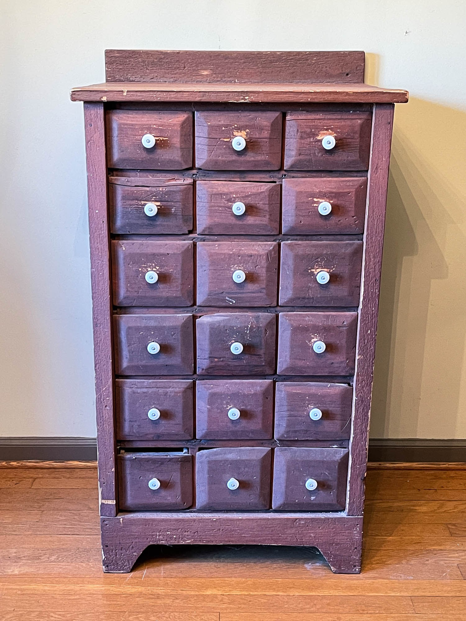 APOTHECARY CABINET WITH EIGHTEEN DRAWERS.: American, early 20th Century (circa 1900). Pine. Case with backsplash, solid ends, and simple feet with chamfered drawer fronts and porcelain knobs. Refinished with edge damage and repairs. 45"h. 25"w
