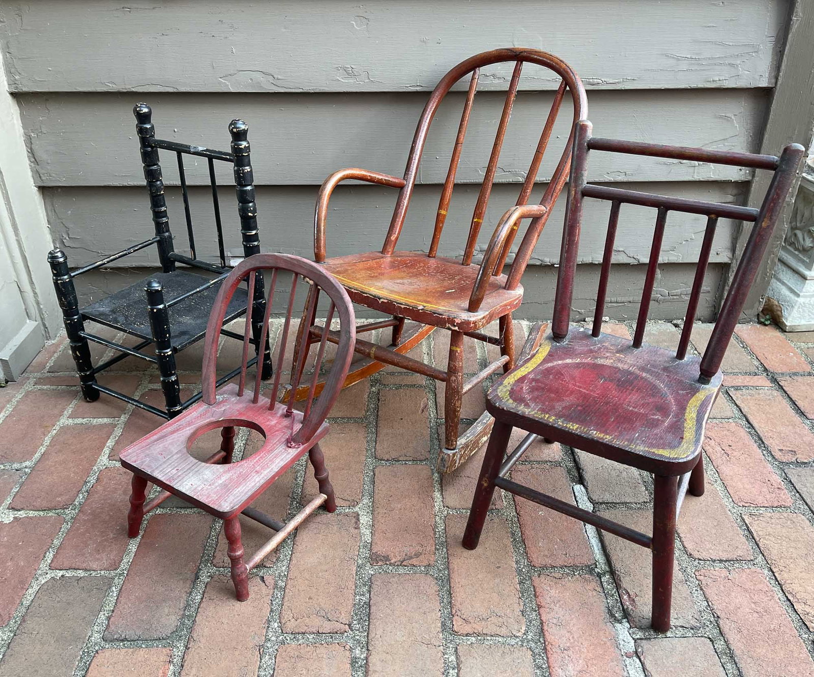 FOUR YOUTH CHAIRS.: American, late 19th early 20th Century. Mixed woods. A bentwood rocking chair with worn red paint, and black and yellow striping. 10.5" seat height 22.5"h. a simple plank seat chair in worn red paint 