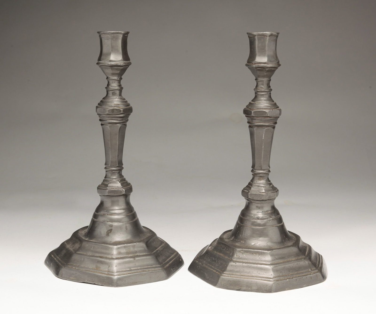 A PAIR OF QUEEN CANDLE STICKS.: French, mid 18th Century. Pewter. Octagonal with stepped bases and paneled stems and candle sockets. Some dents and wear. 9"h.
