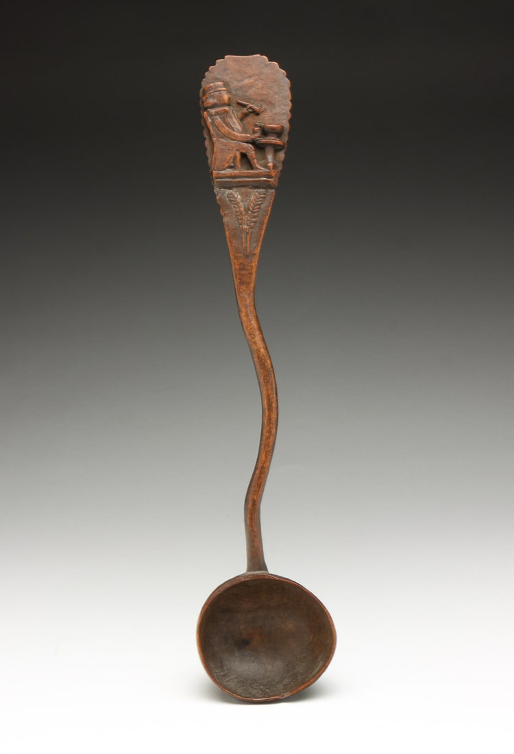 CARVED WOODEN FOLK ART LADLE.: Probably American, 19th Century. Wavy handle with relief of a man in colonial dress, smoking a pipe at a tavern table. Minor edge loss. 10.5"l.