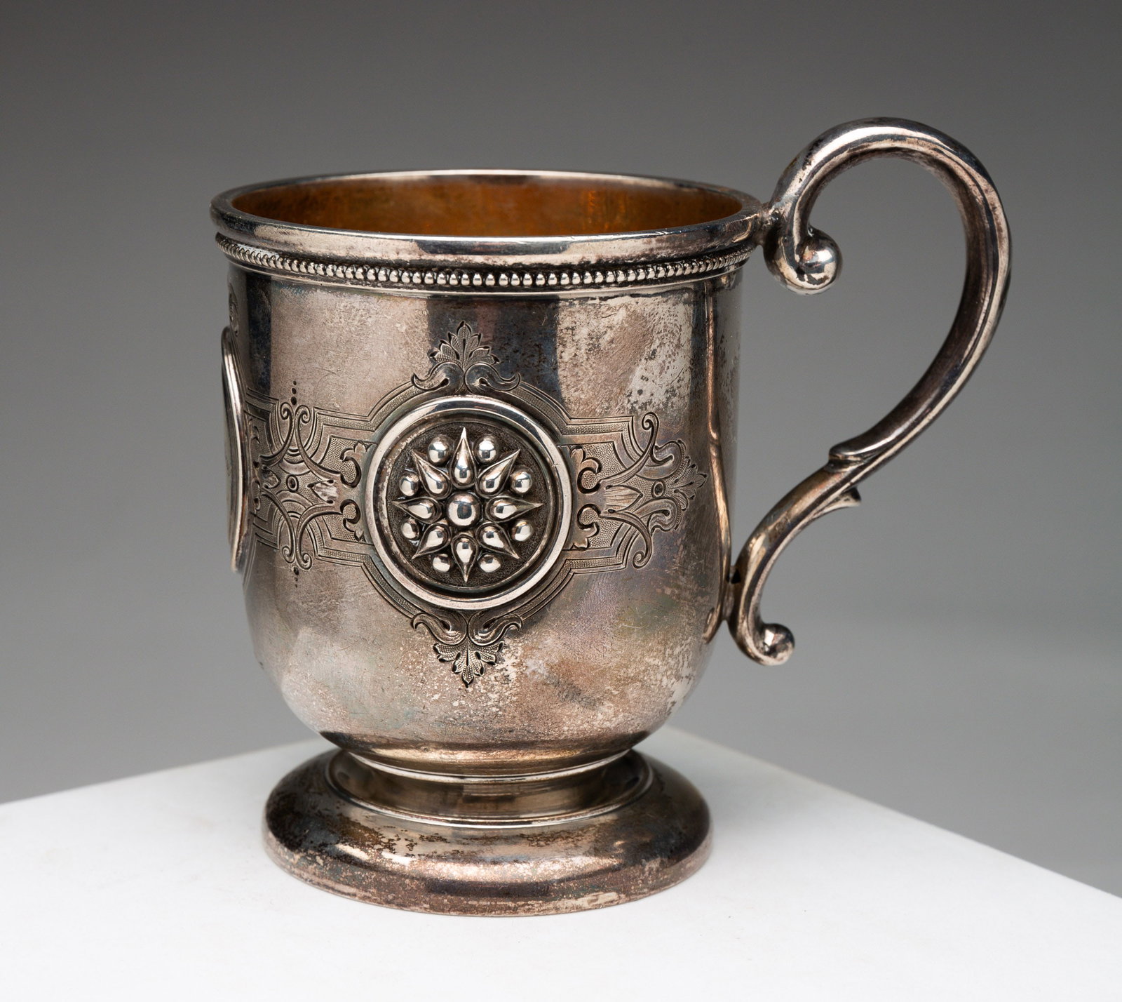 STERLING MUG.: American, dated 1906. Footed mug with Aesthetic Period decoration and vermeil interior. Engraved presentation, dent and wear. 4.25 "h. Approx. 6 ozt.