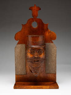 FIGURAL WALL HANGING MATCH SAFE.: Scottish, circa 1900. Hardwood. Shaped back with tulip crest, carved beaded man with top hat match well, lower shelf and two sanded areas for striking matches. 10.5" h. 5.5" w. 2.5" d.