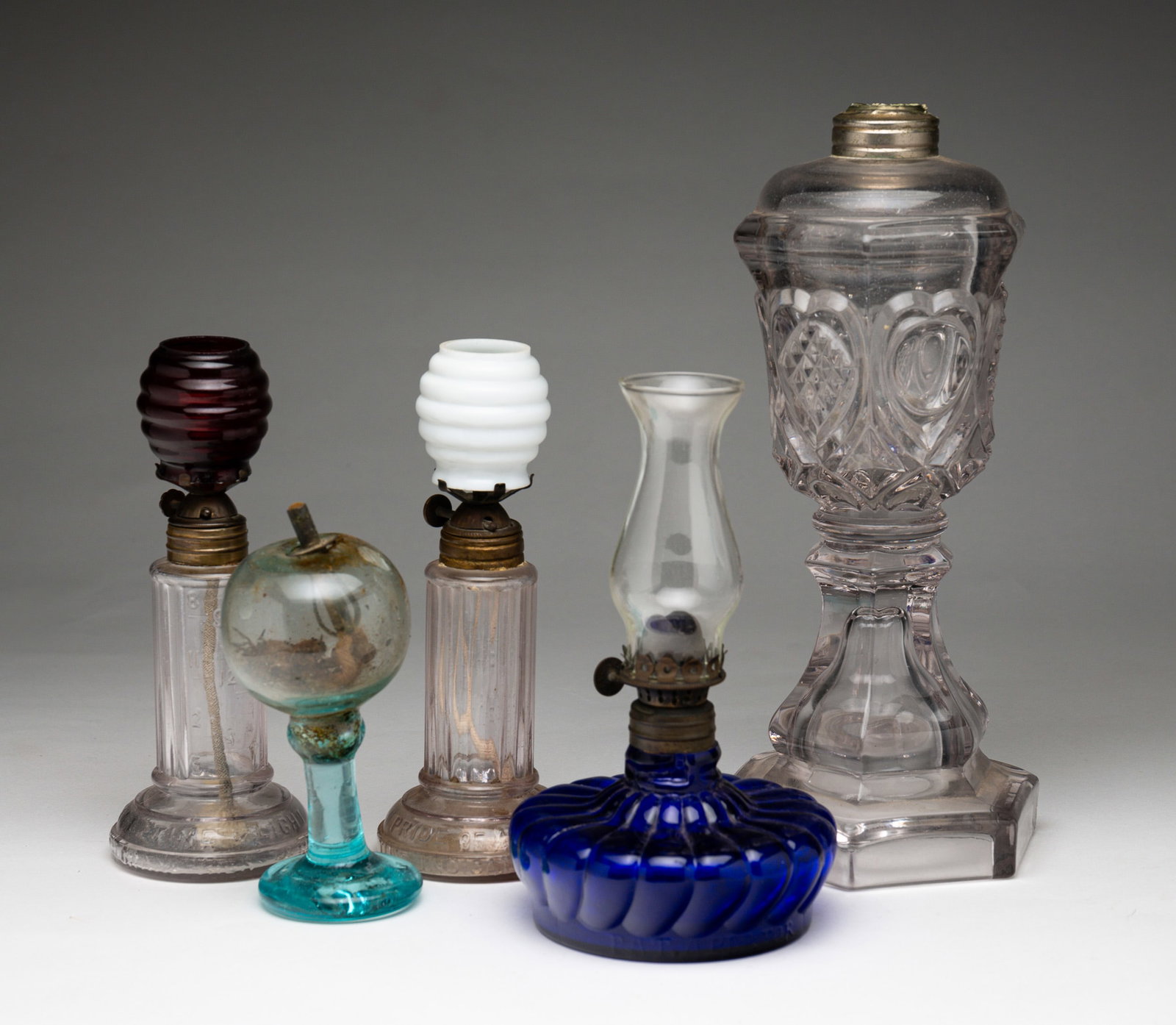 FIVE LAMPS.: American, second half 19th Century. A second period whole oil lamp "Hearts And Diamond" pattern. Non flint, replaced collar and minor wear. 9.75"h., a cobalt bedside lamp with ribbed front, patent dat