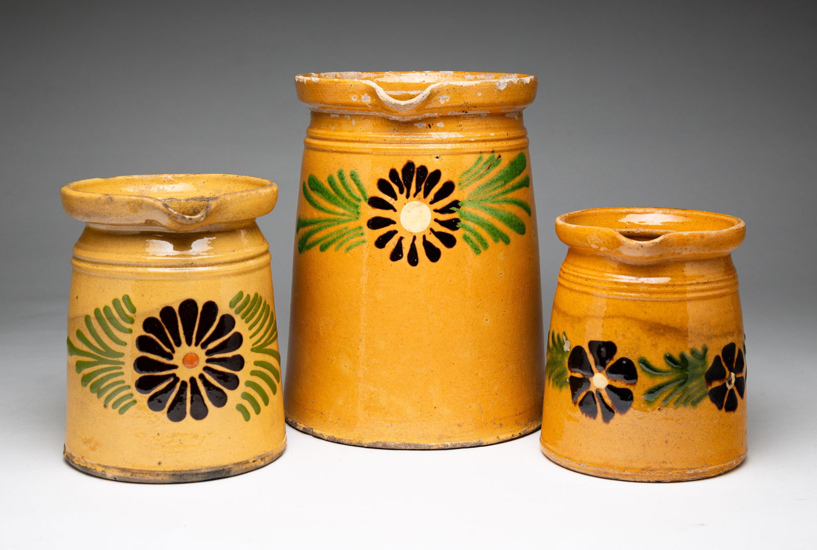 THREE YELLOW WARE DECORATED PITCHERS. (1 of 5)