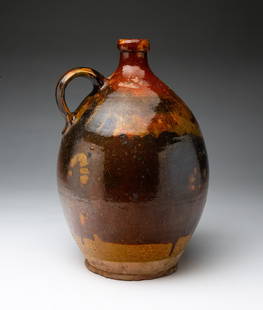 OVOID REDWARE JUG.: American, late 19th century. Red and green mottled glaze, applied strap handle. 12"h. Part of the Bruce & Vivalyn Knight Collection.