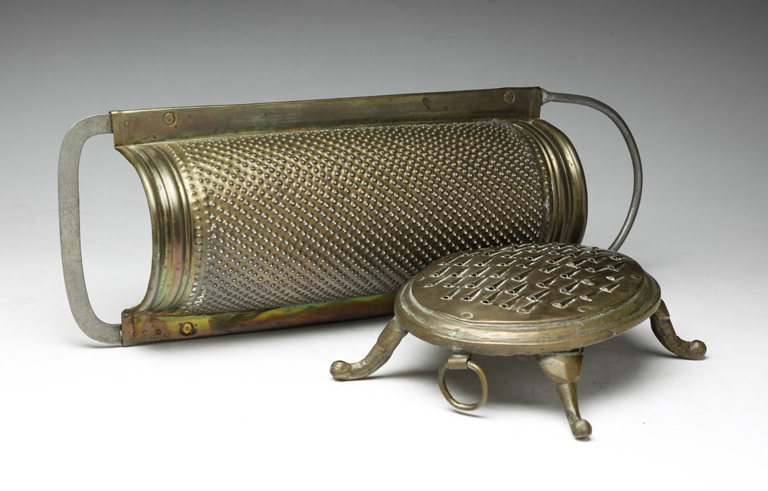TWO BRASS GRATERS.: Probably English, 19th century. Turtle shaped with legs and ring. 2.5"h. 7"l. And semi circular, 16"l. Ex Eve Stone (Massachusetts).