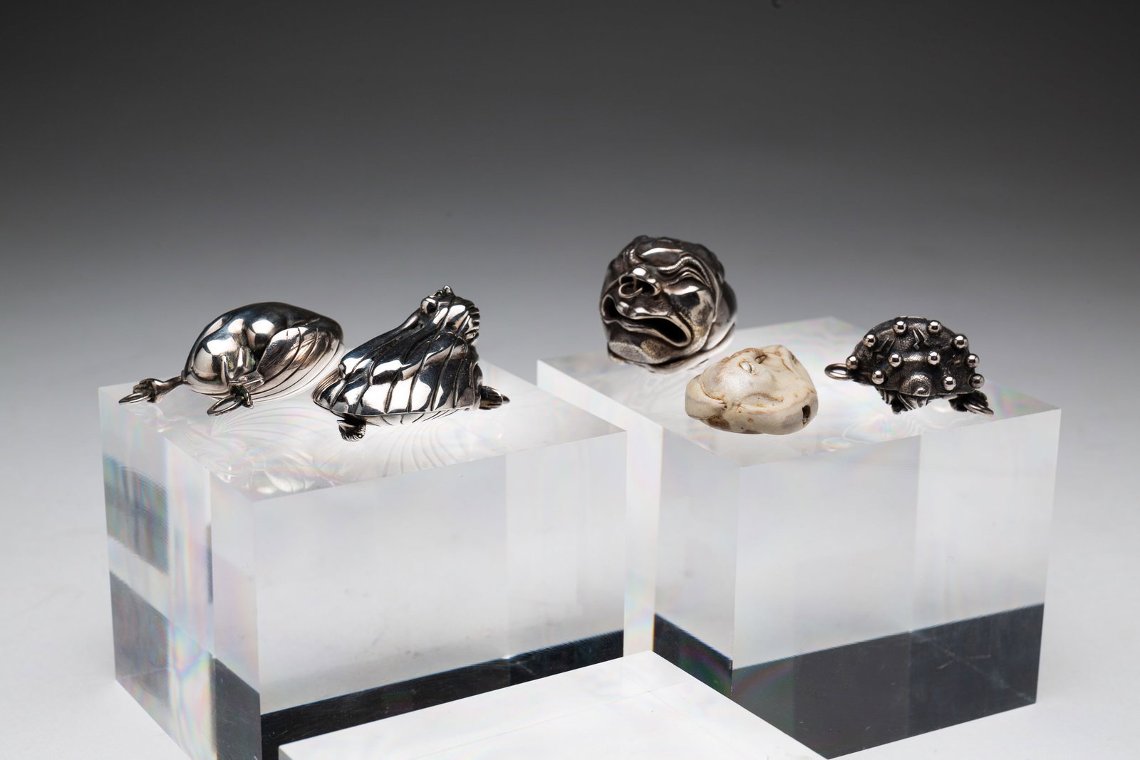 JACLYN DAVIDSON 'NETSUKE' PENDANTS.: American, fourth quarter 20th Century. Group of four silver pendants, one marked 'sterling', one marked 'S.S.', pieces signed 'Jacklyn' and numbered. Together with carved bead/pendant.