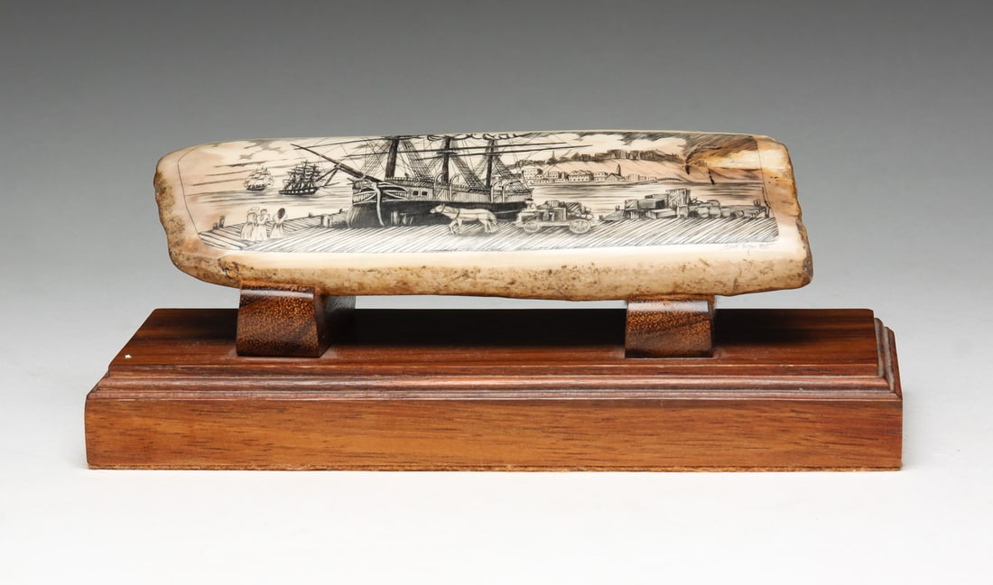 SCOTT PARKER DECORATED SCRIMSHAW TUSK.: American, dated 1985. Signed shipyard scene decorated on fossilized scrimshaw tusk. With wooden stand. 2"h. 6"w. On stand 7.25"w.