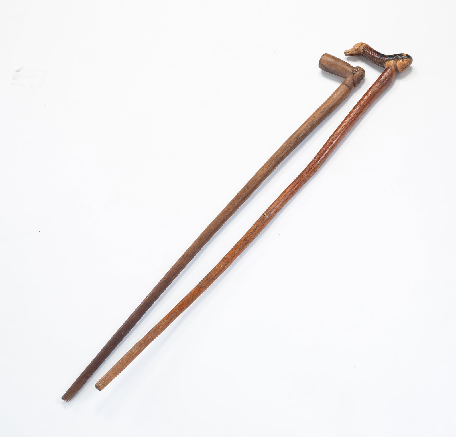 TWO FOLK ART CARVED WOOD CANES.: American, late-19th Century. Dog cane with allegorical woman, and another with faces (appear to be bone). Both 33"h.