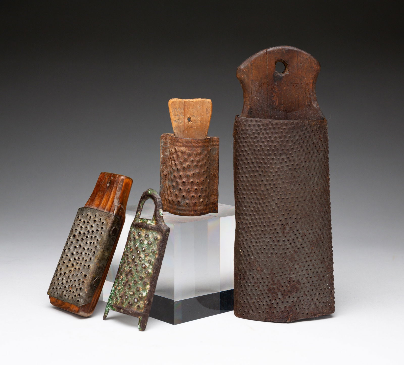 GROUP OF SCARCE COUNTRY PIERCED TIN NUTMEG GRATERS.: American, 1800-1860. Tin and wood collection of four graters with three wall-hanging (two are diminutive), and one diminutive painted metal. The largest, 7".