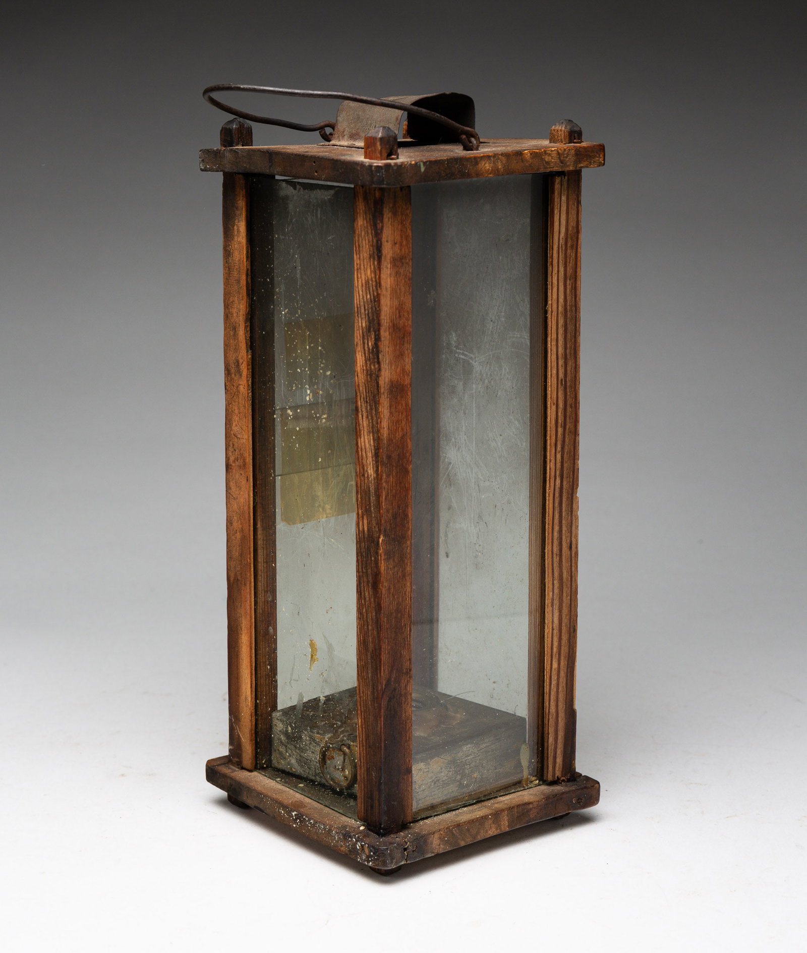 WOOD BARN LANTERN.: American or European, late 18th - early 19th Century. Four-glazed sides, tin hood, and bent iron handle. The interior with a rare, square tin font or oil reservoir. Overall, 4"w., 10"h. From the colle