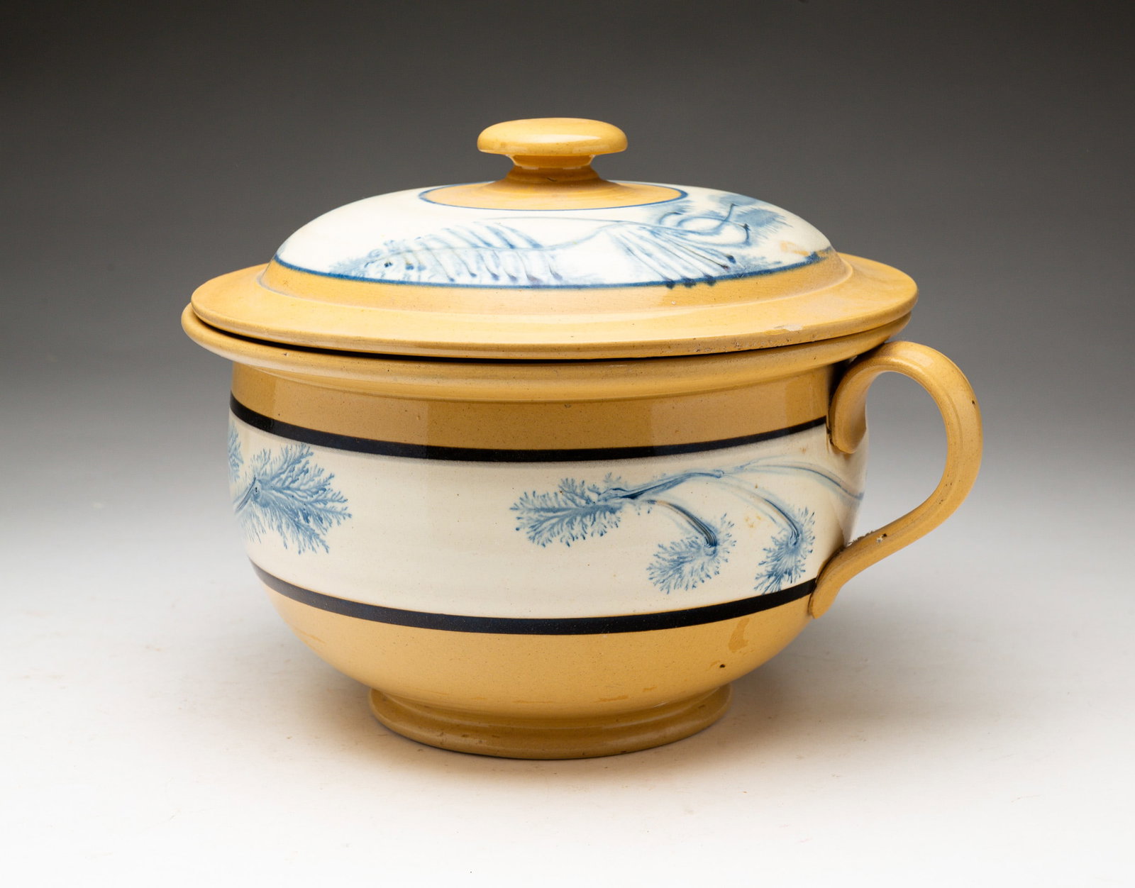 YELLOW WARE LIDDED CHAMBER POT WITH MOCHA DECORATION.: England, second half 19th Century. Typical shape with cream bands and blue seaweed decoration. Some chips and lime residue. 7.25 "h.