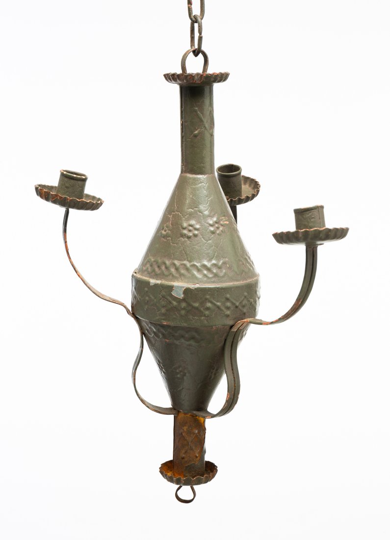 PUNCHED TIN THREE-LIGHT CHANDELIER.: American or European, 19th / 20th century. Tin. Three-light punched tin chandelier. Embossed design with tole printed caps. Green over red paint. 14"h. From the collection of the late Audrey Caspari (