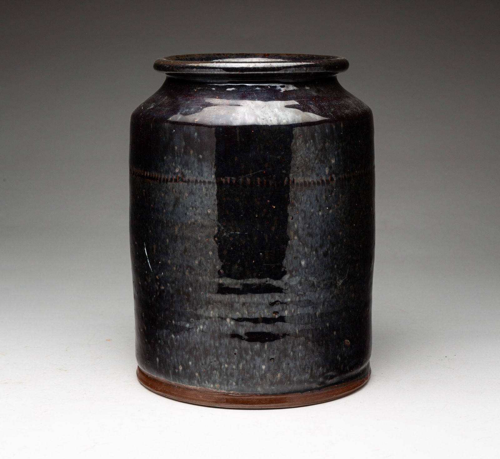 REDWARE JAR.: American, second half 19th Century. Cylinder shape with flared lip and coggled band. Manganeseglaze has some wear. 9.25"h.
