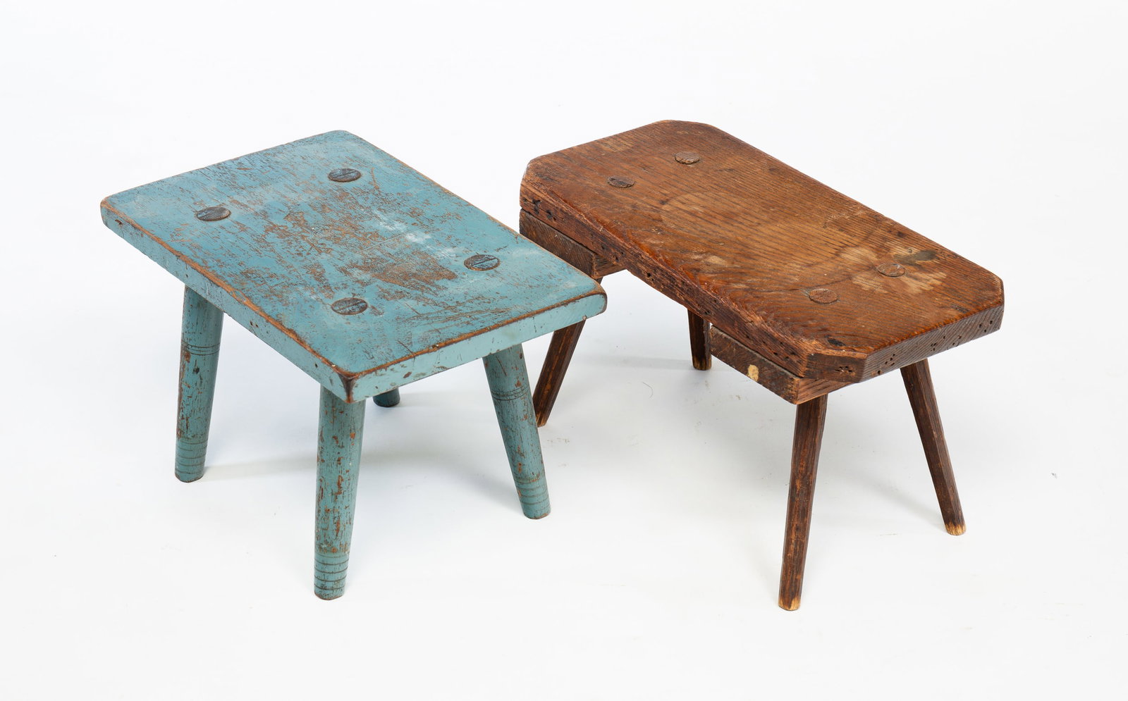 TWO COUNTRY FOOTSTOOLS.: American, mid 19th Century. Oak. One has turned legs and worn blue paint, 8"h. 12.5"w. 8"d. and the second has cut corners on top and pencil post splayed legs. 8"h. 14"w. 7"d.