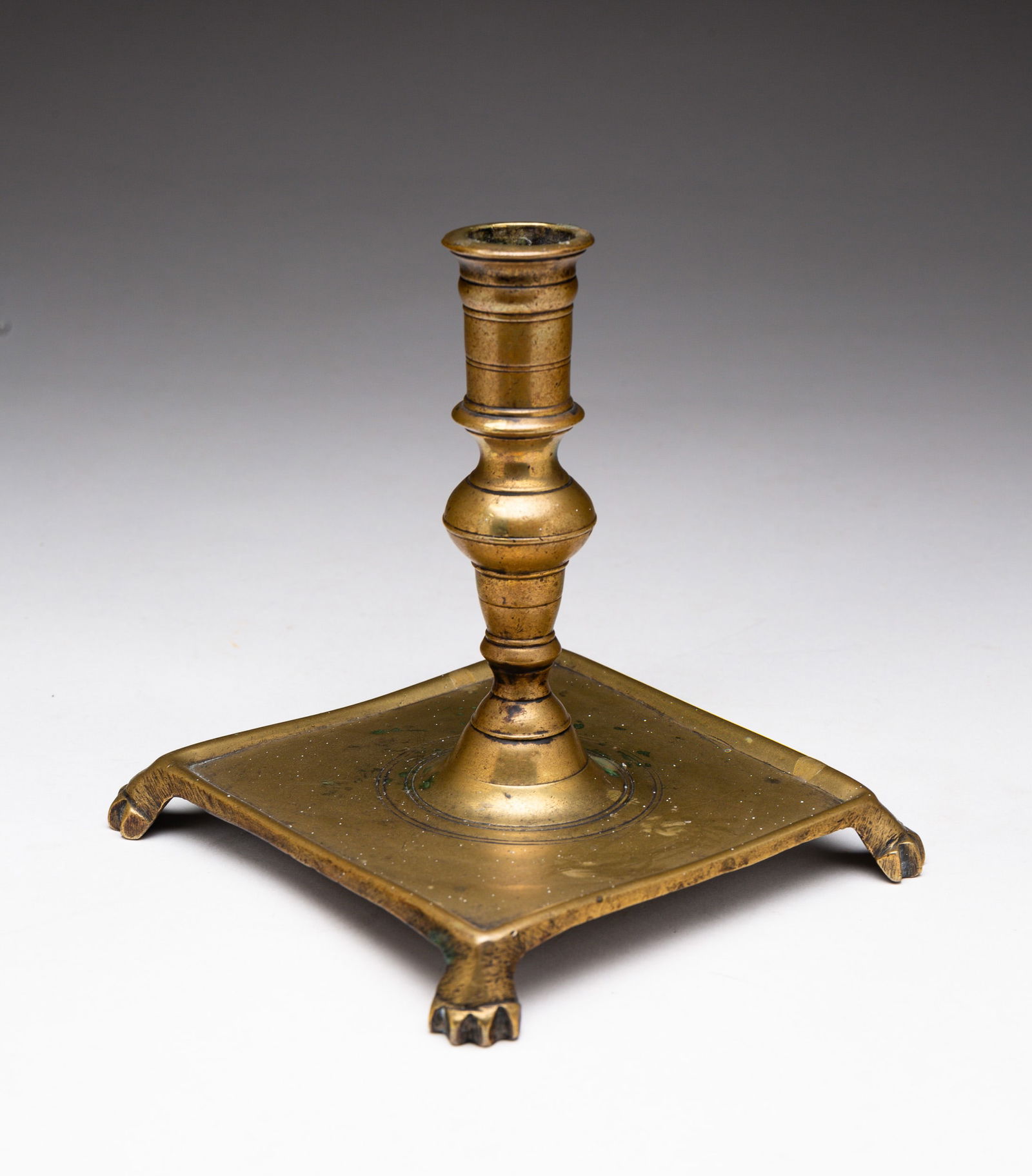EARLY CANDLESTICK.: European (likely Spanish), early 18th Century. Brass. Ballister stem, square base with paw feet. 5.75"h.
