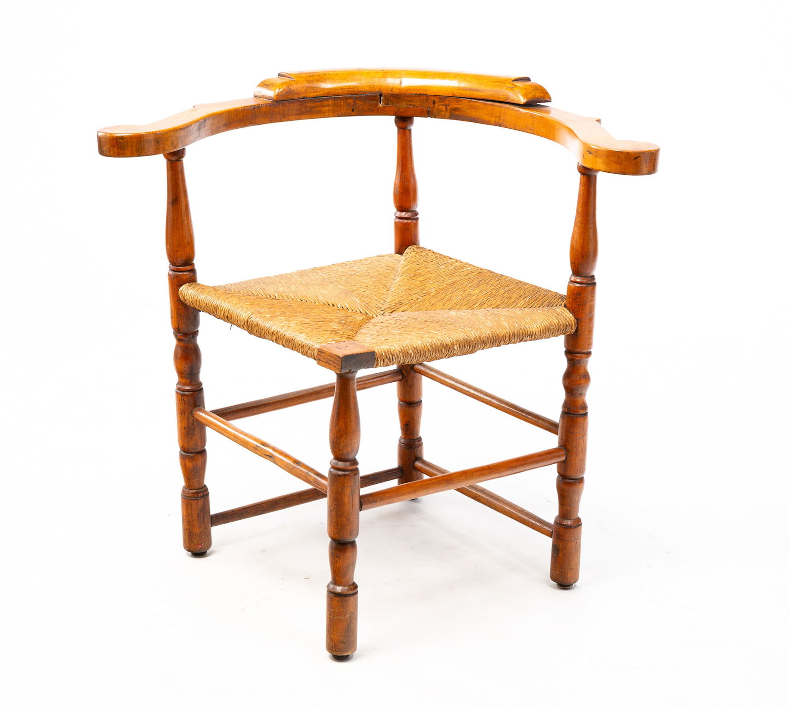 COUNTRY CORNER CHAIR.: American, 18th Century. Turned-maple rush seat corner chair with scroll back crest, boldly shaped arms, turned supports and legs. Single spindle stretchers along the front; double stretchers in the re