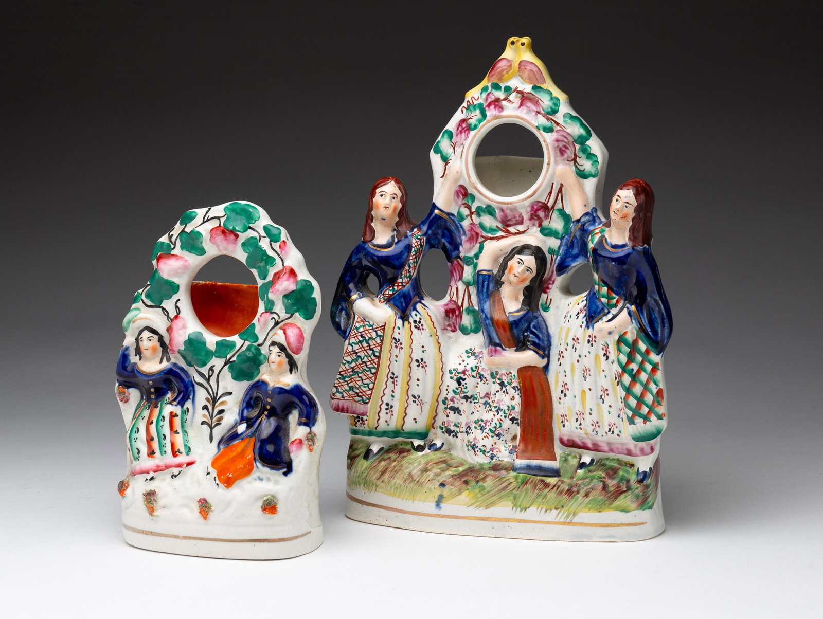 TWO STAFFORDSHIRE WATCH HUTCHES.: English, second-half 19th Century. Both have colorful polychrome decoration. The larger has three female figures and a pair lovebirds' finial. Professional repair to back. 10.75"h. The smaller has a m