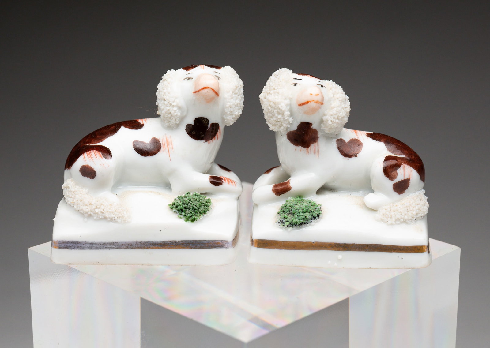 PAIR OF STAFFORDSHIRE PORCELAIN SPANIELS.: English, second-half 19th Century. Two brown spaniels with sanded ears and tails laying on pillows. 1.75"h. 1.75"w.