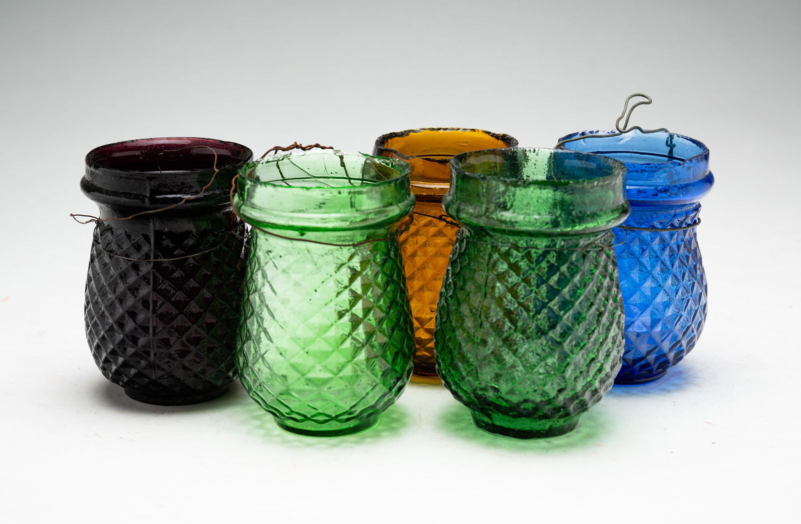 FIVE POLYCHROME CHRISTMAS TREE LANTERNS.: American, fourth quarter 19th Century. Two green, one blue, one purple and one amber. With textured quilted pattern. 3.75"h.